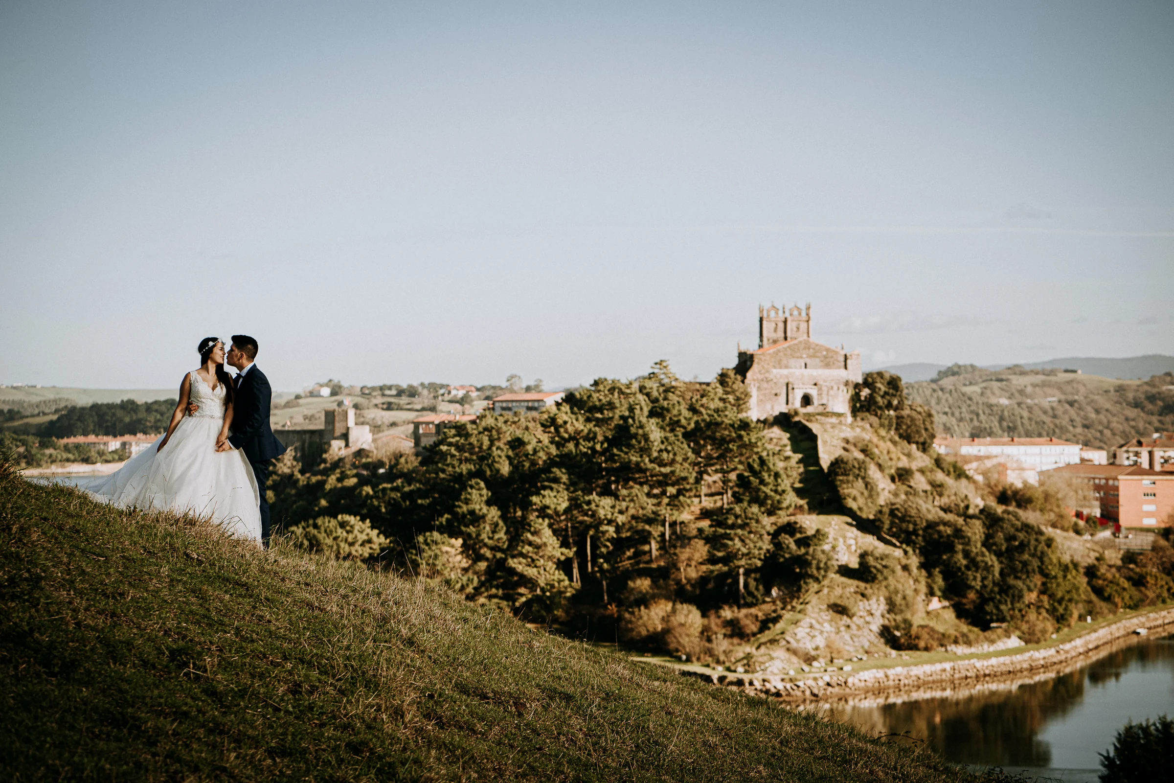 Pareja con vistas al estuario y al paisaje urbano costero durante una sesión de postboda en El Molino, cerca de Llanes, Asturias.