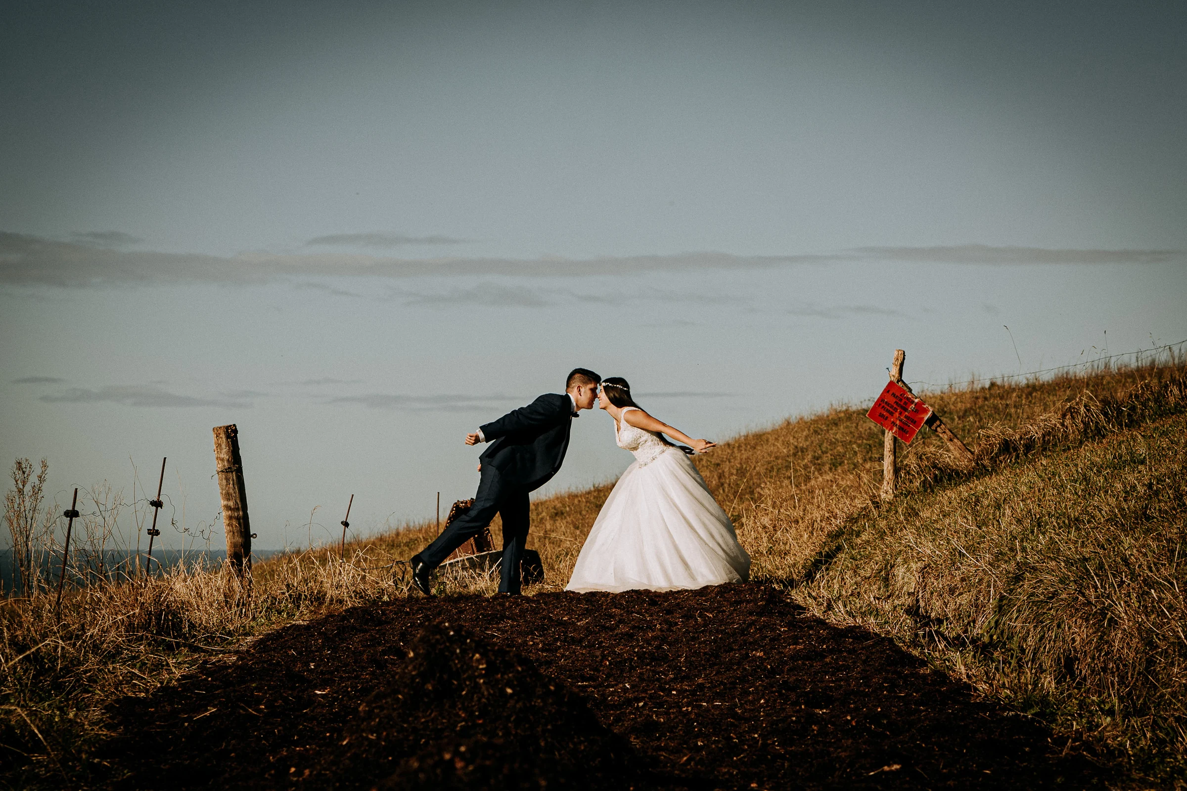 Pareja corriendo por una ladera junto a la costa durante una sesión de postboda en El Molino, cerca de Llanes, Asturias.
