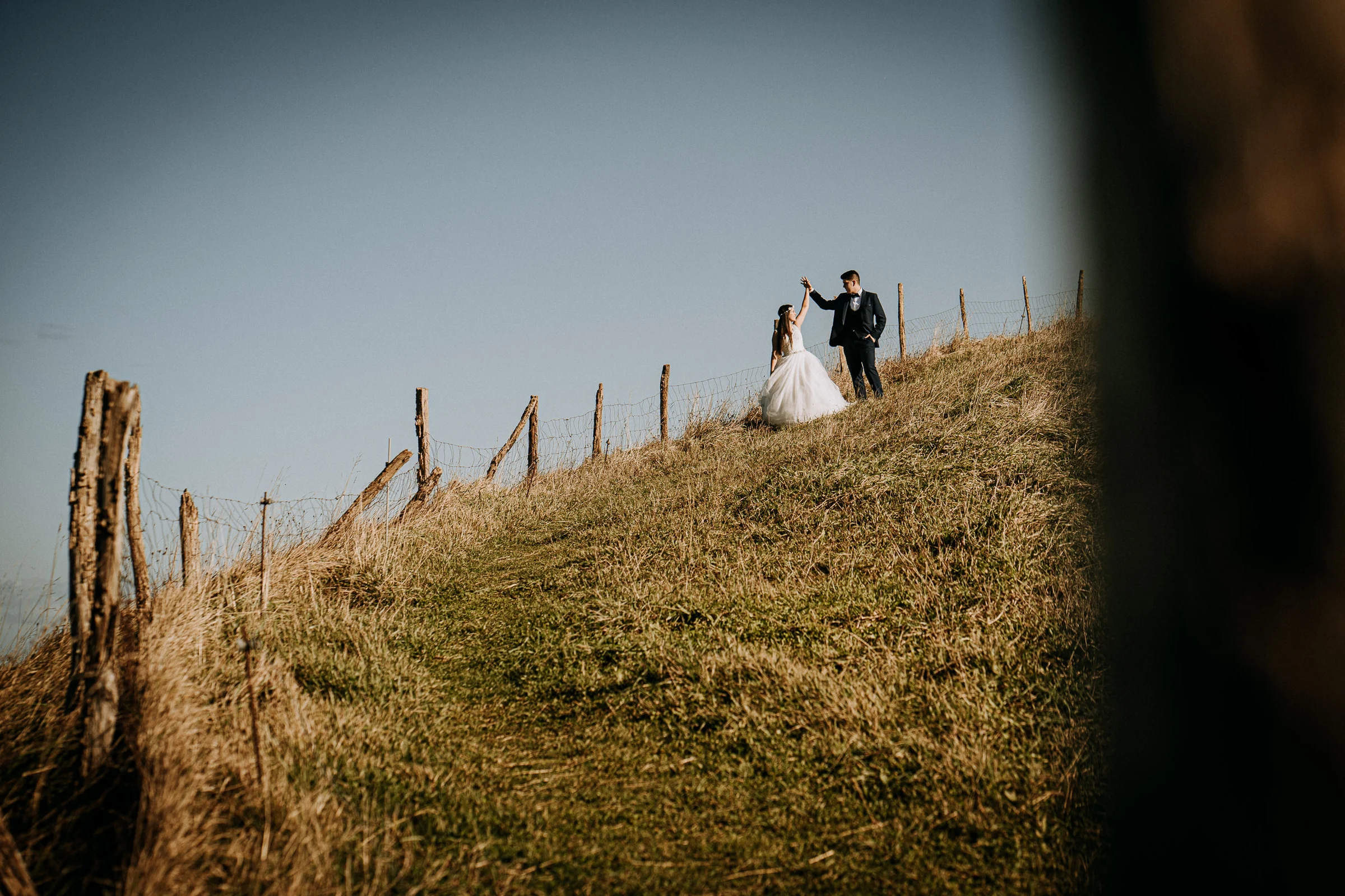 Pareja en lo alto de la colina con paisaje abierto durante una sesión de postboda en El Molino, cerca de Llanes, Asturias.