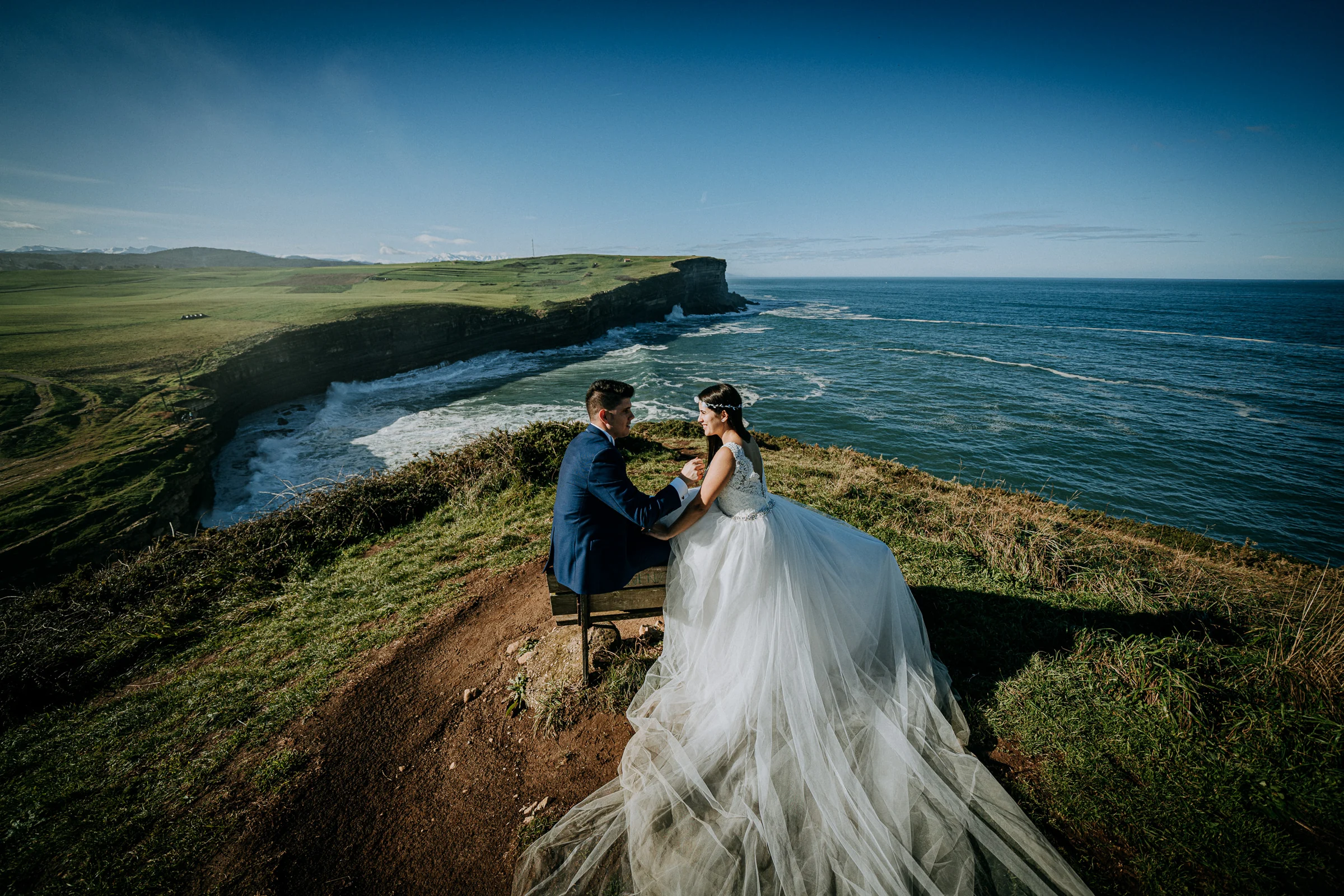 Pareja en primer plano sobre el acantilado y el mar durante una sesión de postboda en El Molino, cerca de Llanes, Asturias.