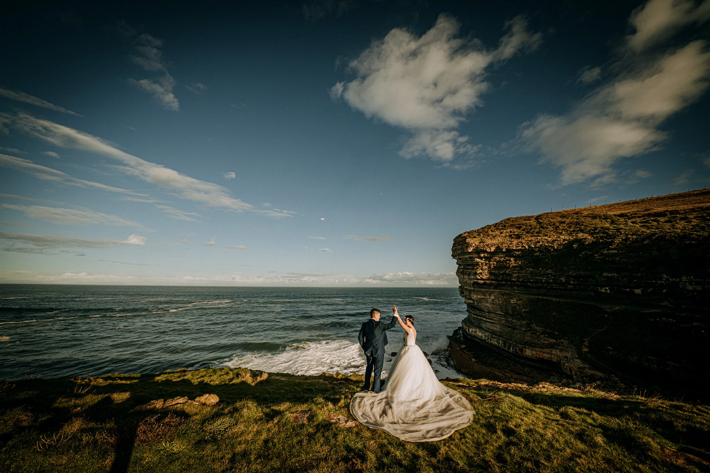 Pareja en un acantilado con cielo y mar como protagonistas durante una sesión de postboda en El Molino, cerca de Llanes, Asturias.