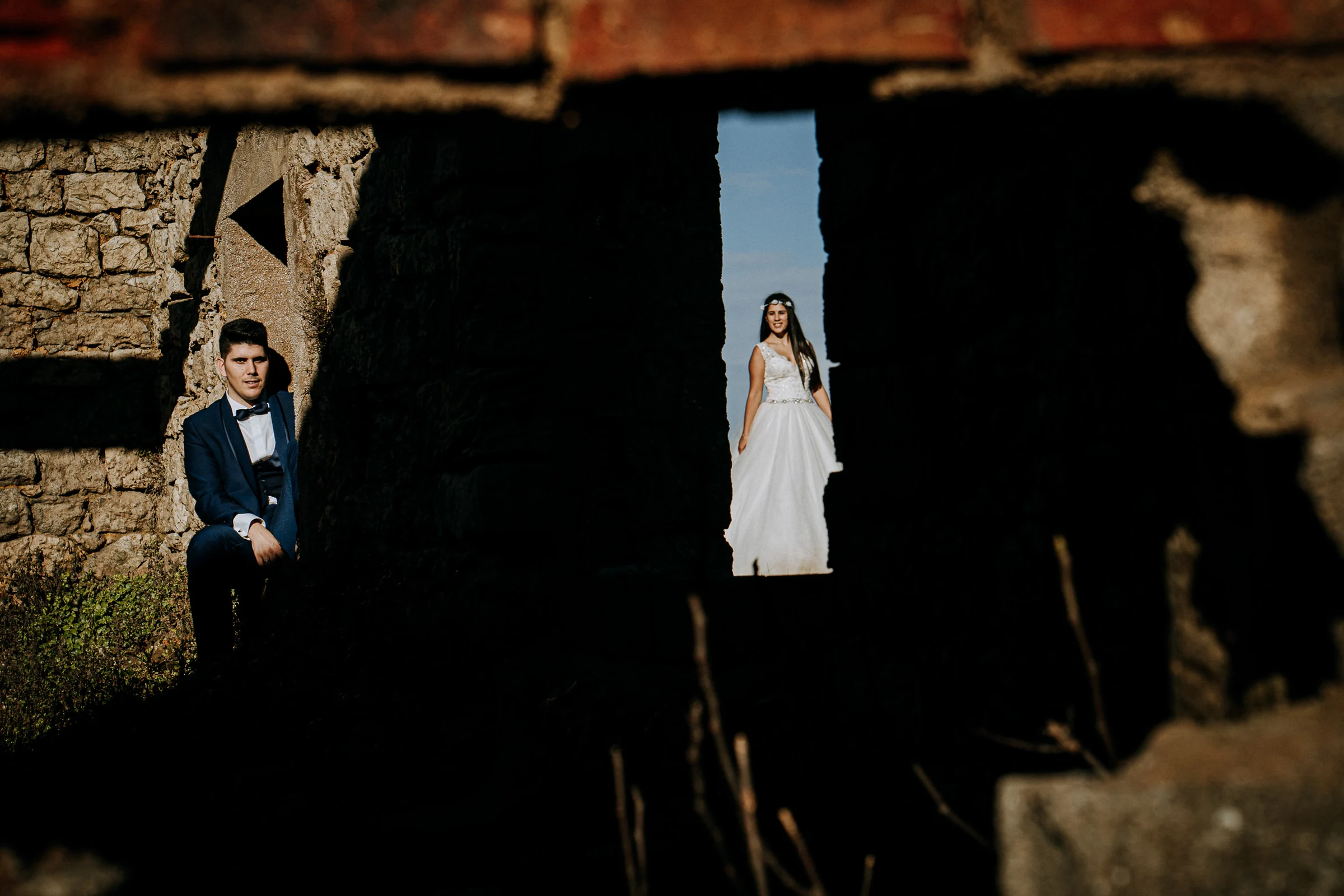 Pareja enmarcada entre las ruinas de piedra durante una sesión de postboda en El Molino, cerca de Llanes, Asturias.