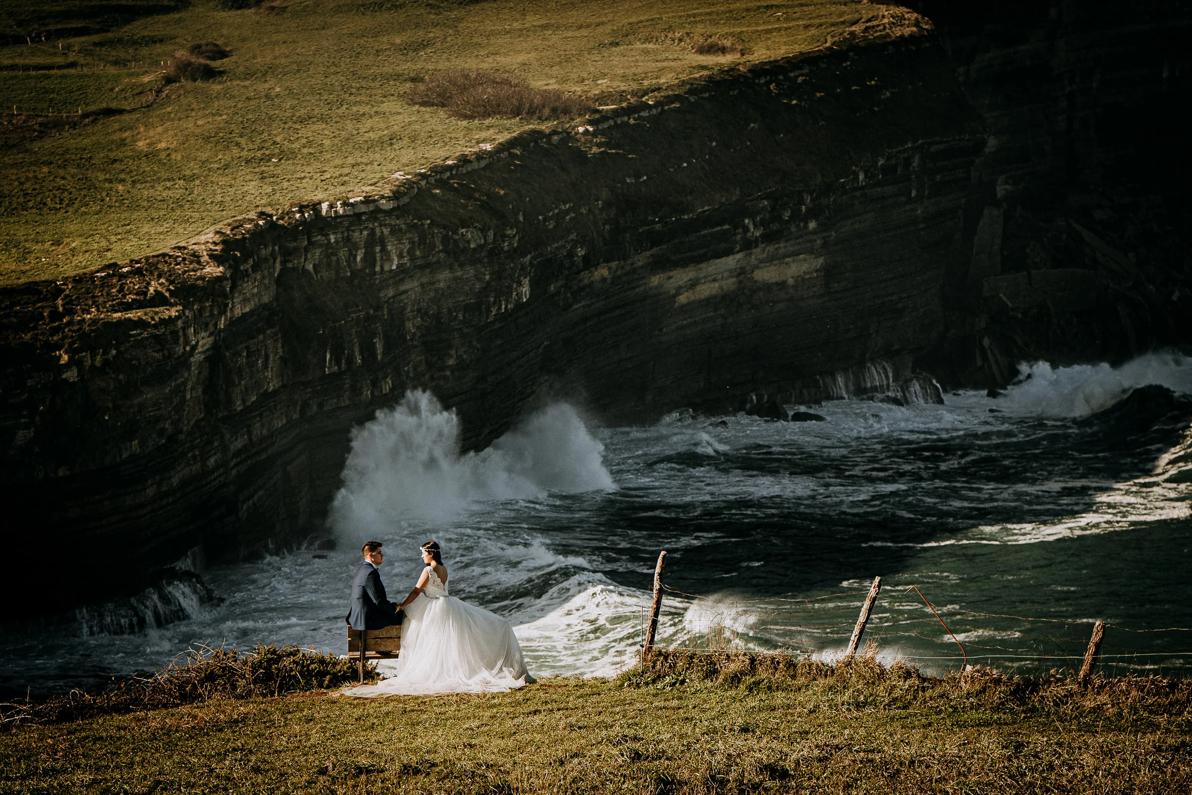 Pareja junto a los acantilados con el mar de fondo durante una sesión de postboda en El Molino, cerca de Llanes, Asturias.