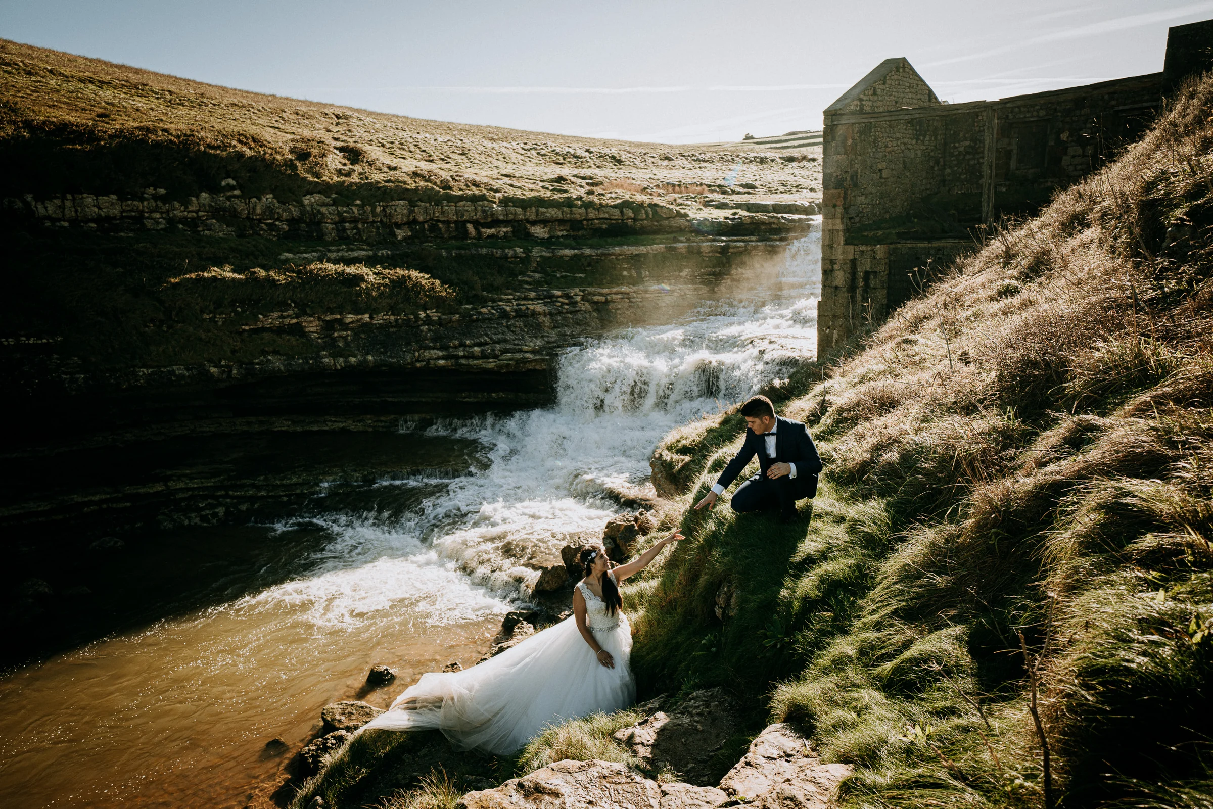 Pareja junto a una cascada natural próxima al mar durante una sesión de postboda en El Molino, cerca de Llanes, Asturias.