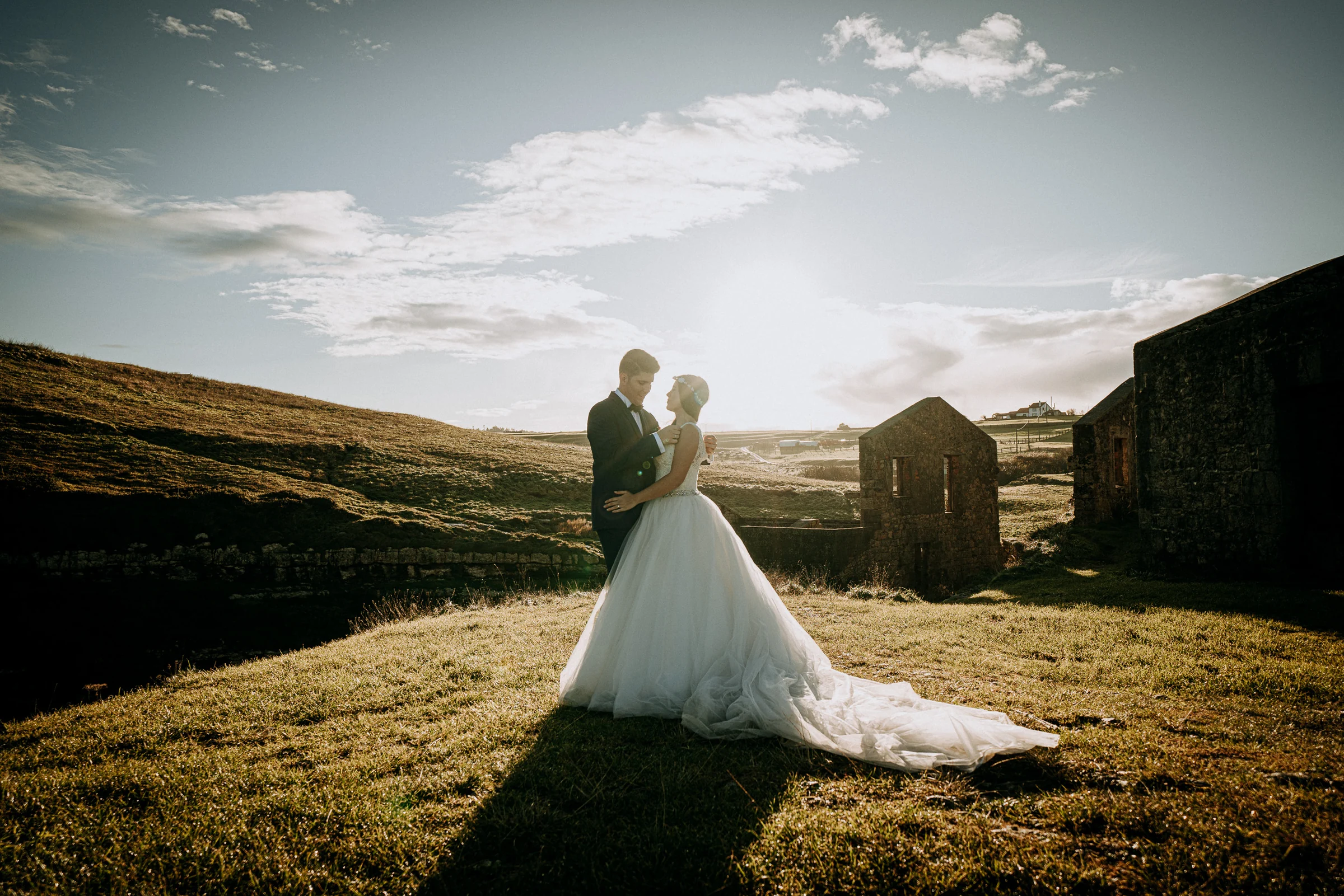 Pareja junto a unas ruinas de piedra con luz de atardecer durante una sesión de postboda en El Molino, cerca de Llanes, Asturias.