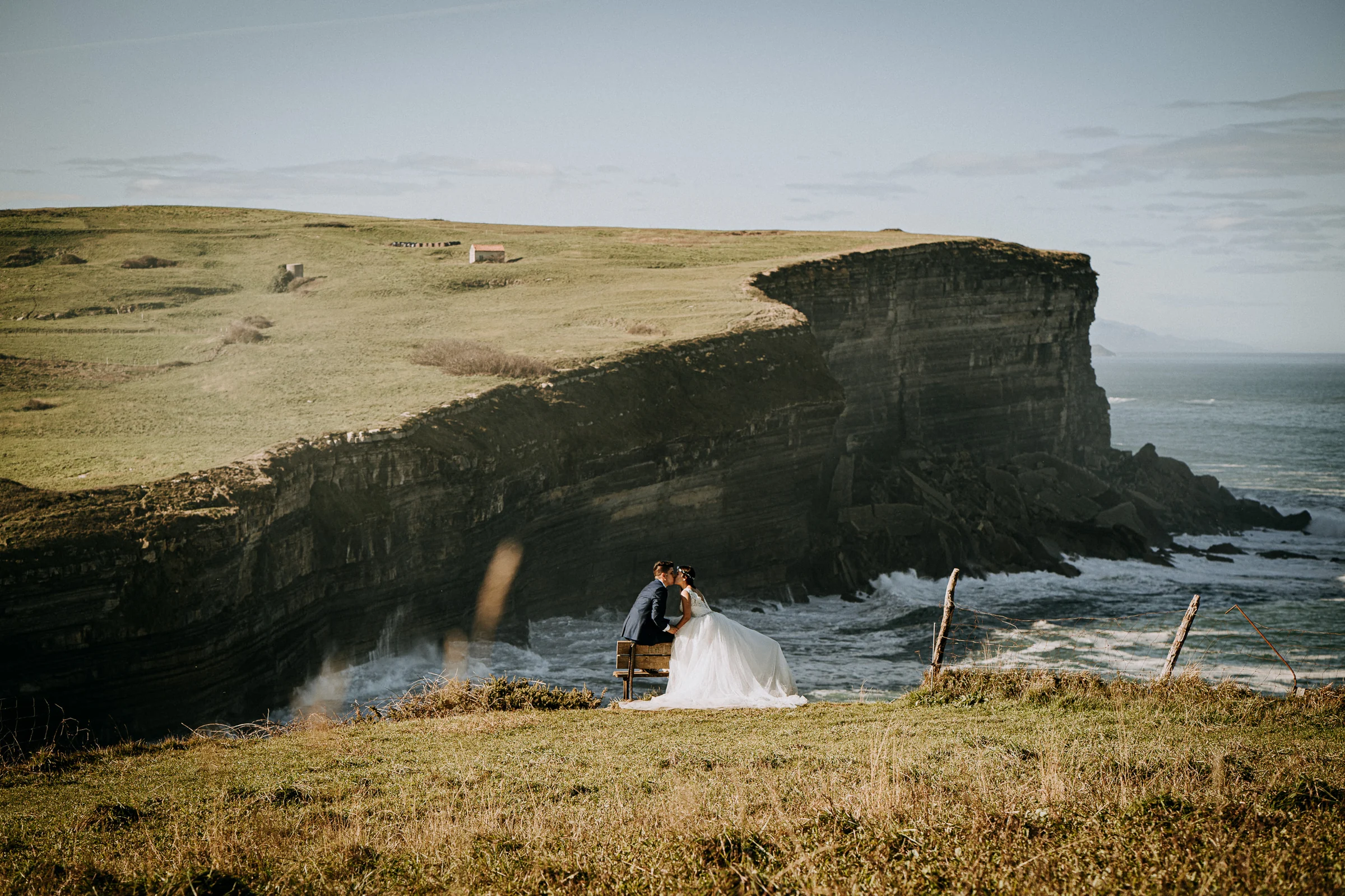 Pareja posando en un mirador natural sobre el océano durante una sesión de postboda en El Molino, cerca de Llanes, Asturias.