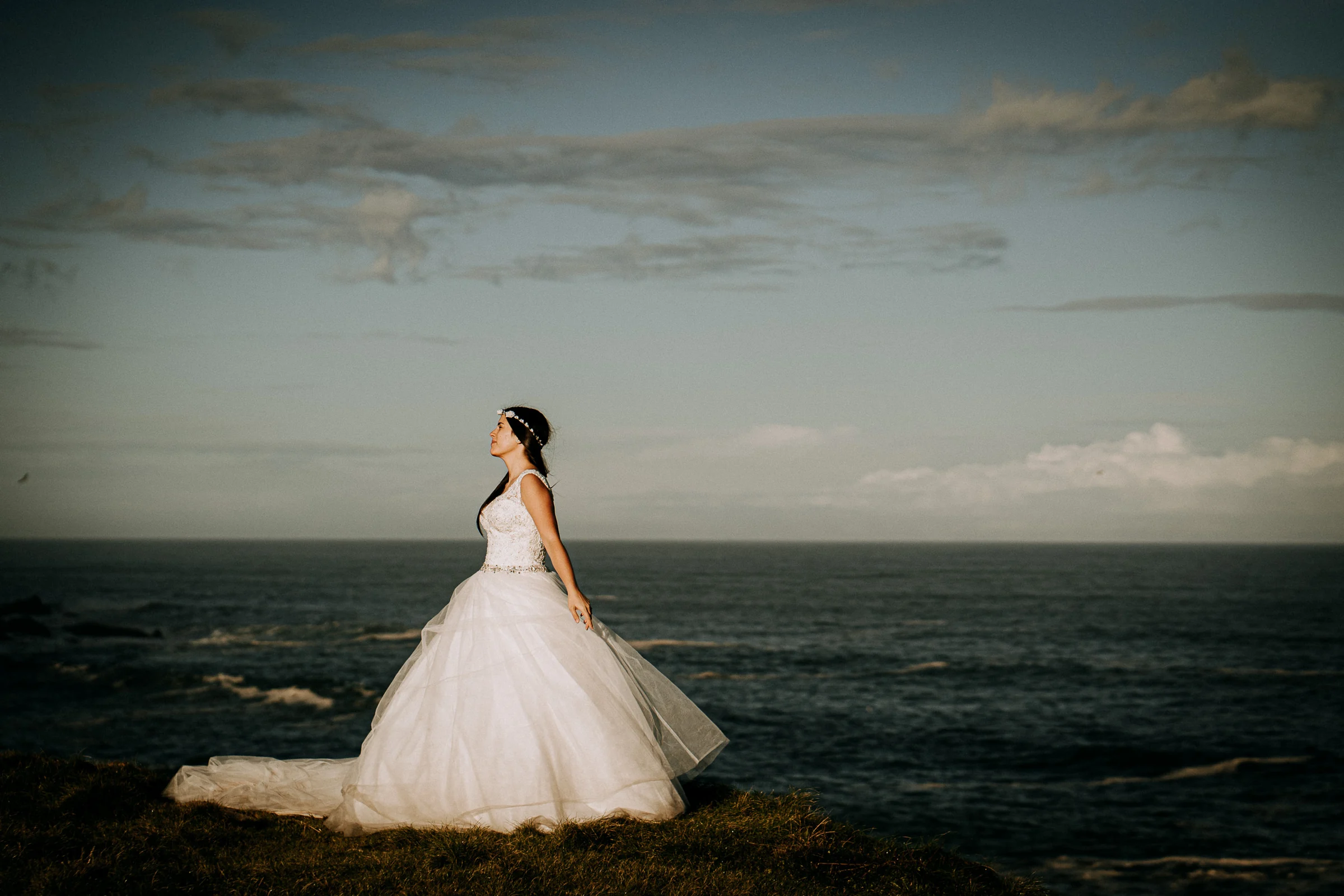 Retrato de la novia sola frente al océano durante una sesión de postboda en El Molino, cerca de Llanes, Asturias.