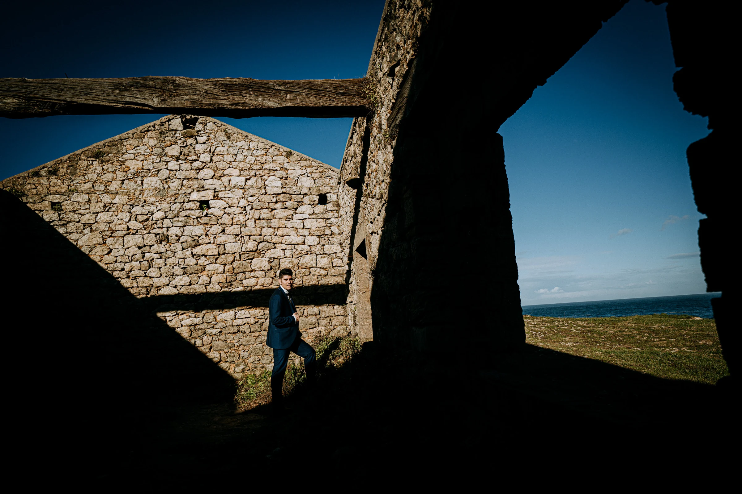 Retrato del novio entre luces y sombras de unas ruinas durante una sesión de postboda en El Molino, cerca de Llanes, Asturias.