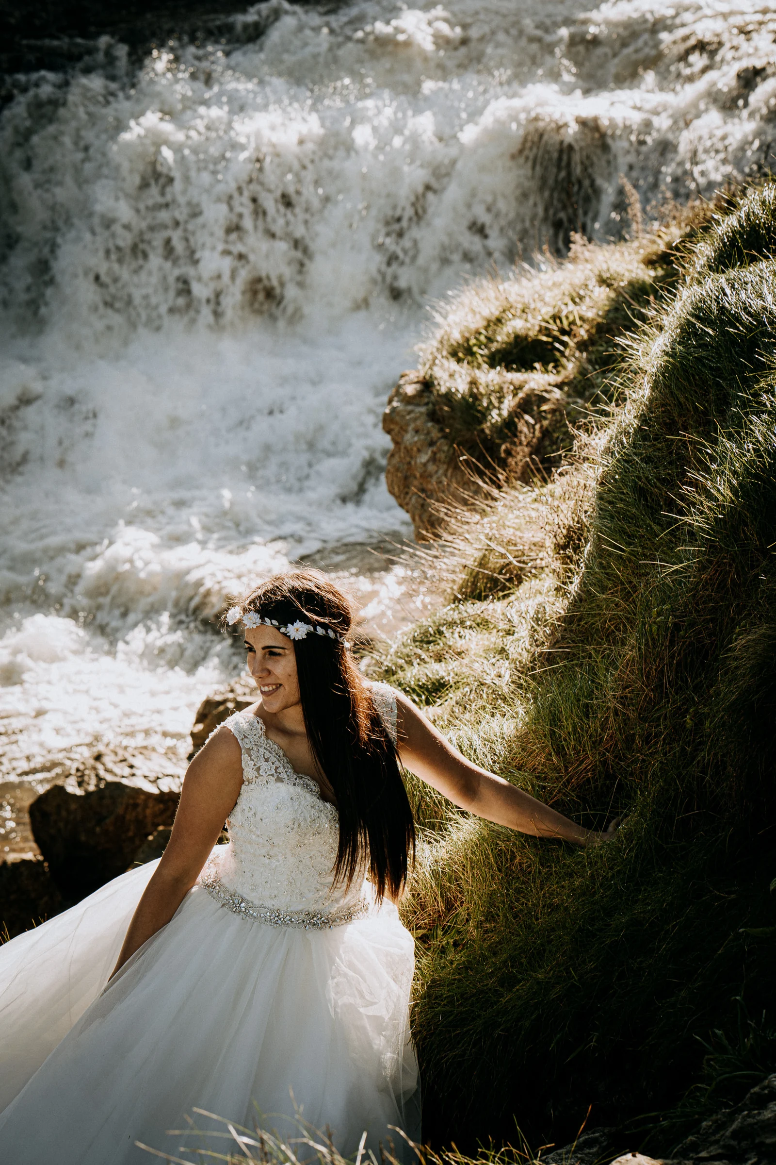 Retrato vertical de la novia junto a la cascada durante una sesión de postboda en El Molino, cerca de Llanes, Asturias.