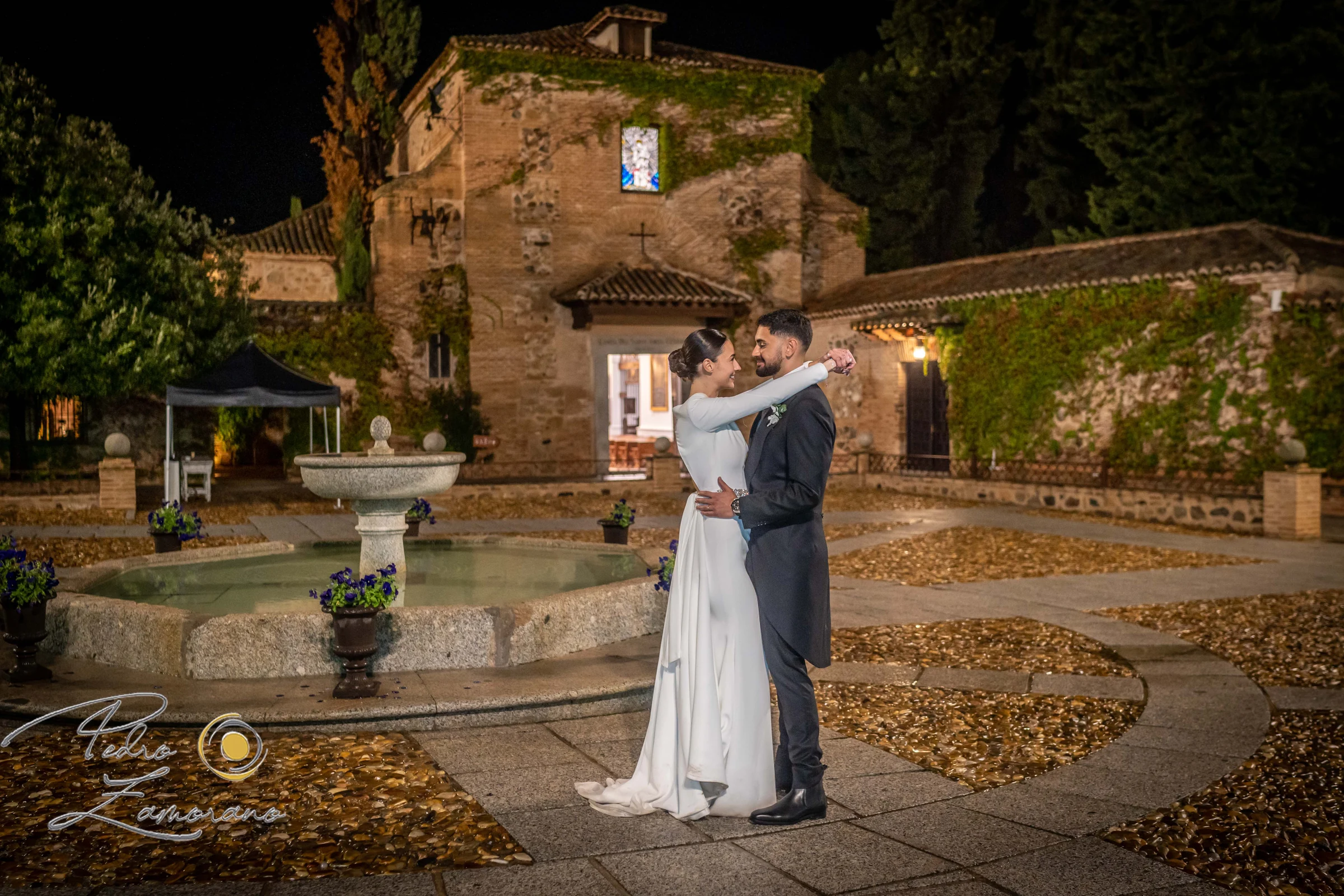 Hora azul: pareja junto a la fuente con la finca ya iluminada