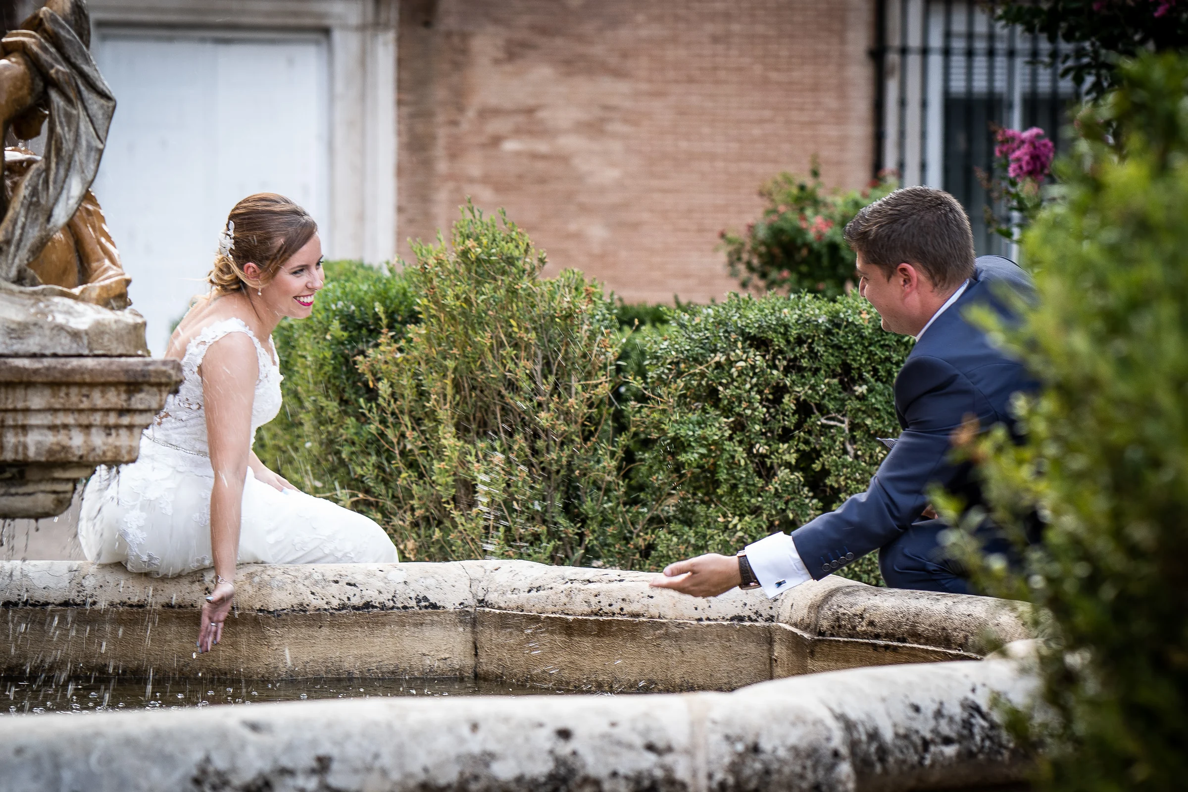 Dani y Nerea jugando con el agua de una fuente en Aranjuez