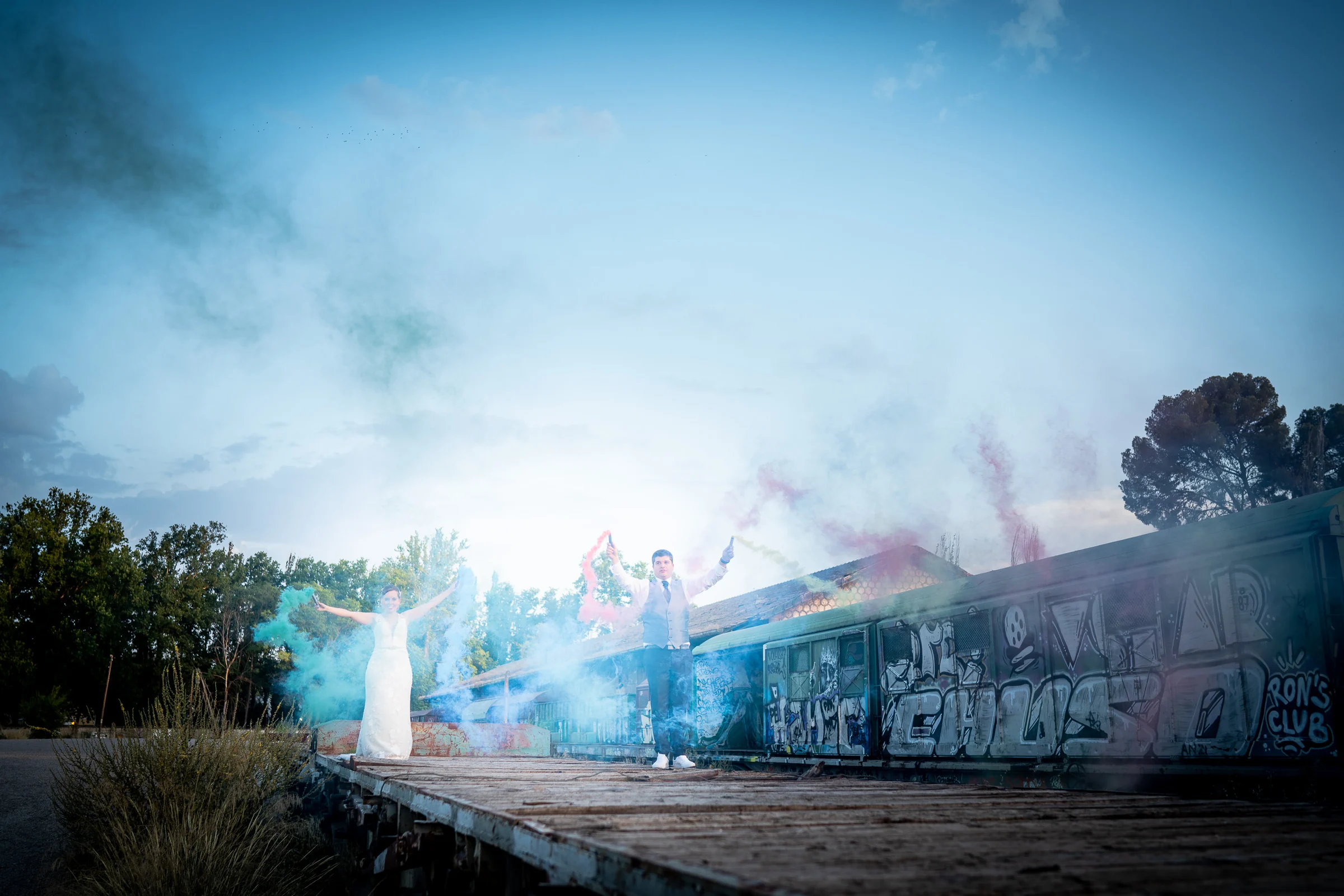 Dani y Nerea rodeados de humo de colores junto a vagones en Aranjuez