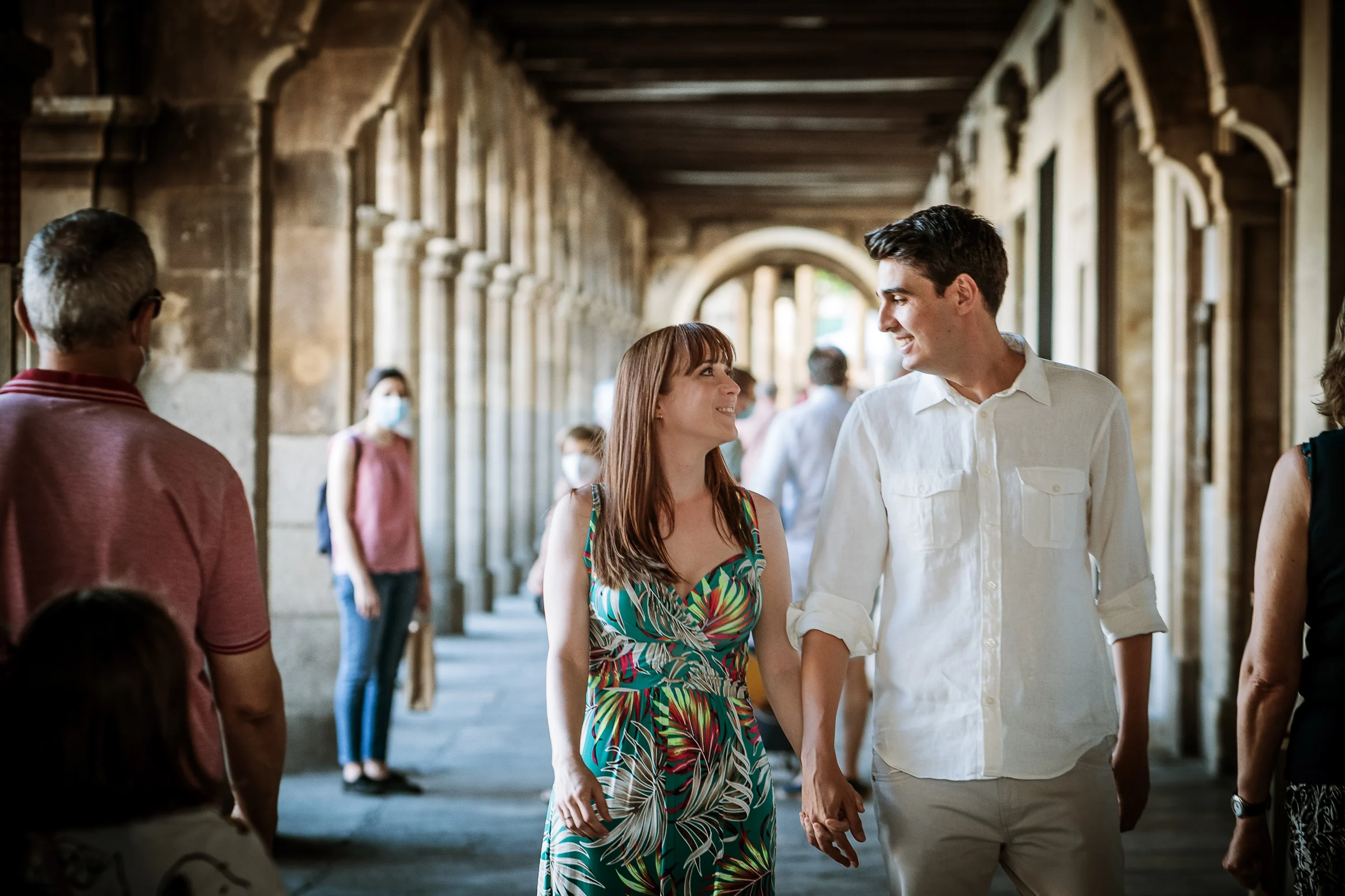 David y Noelia pasean sonrientes bajo los soportales de la Plaza Mayor durante su preboda en Salamanca.