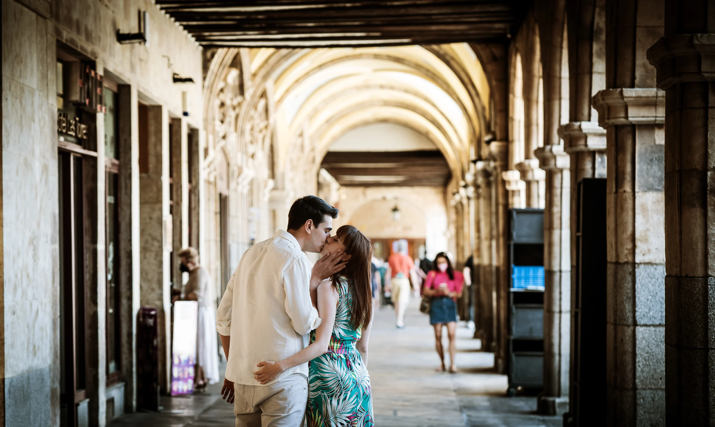 David y Noelia comparten un beso bajo las arcadas de la Plaza Mayor durante su sesión de preboda en Salamanca.