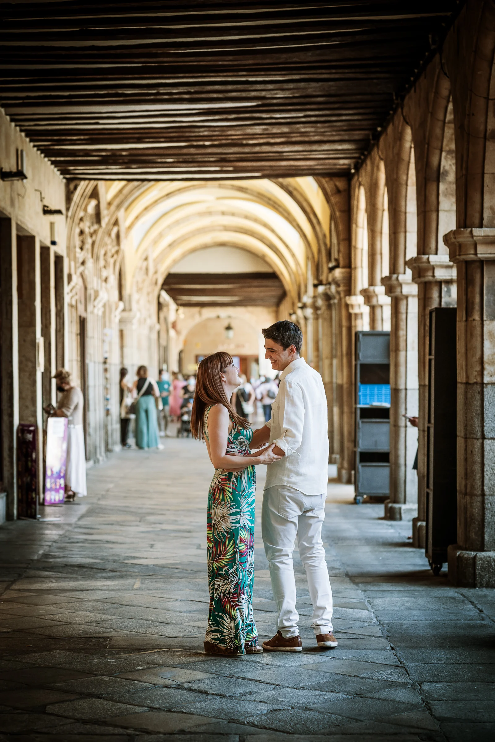 David y Noelia se abrazan bajo una sucesión de arcos en la Plaza Mayor de Salamanca.