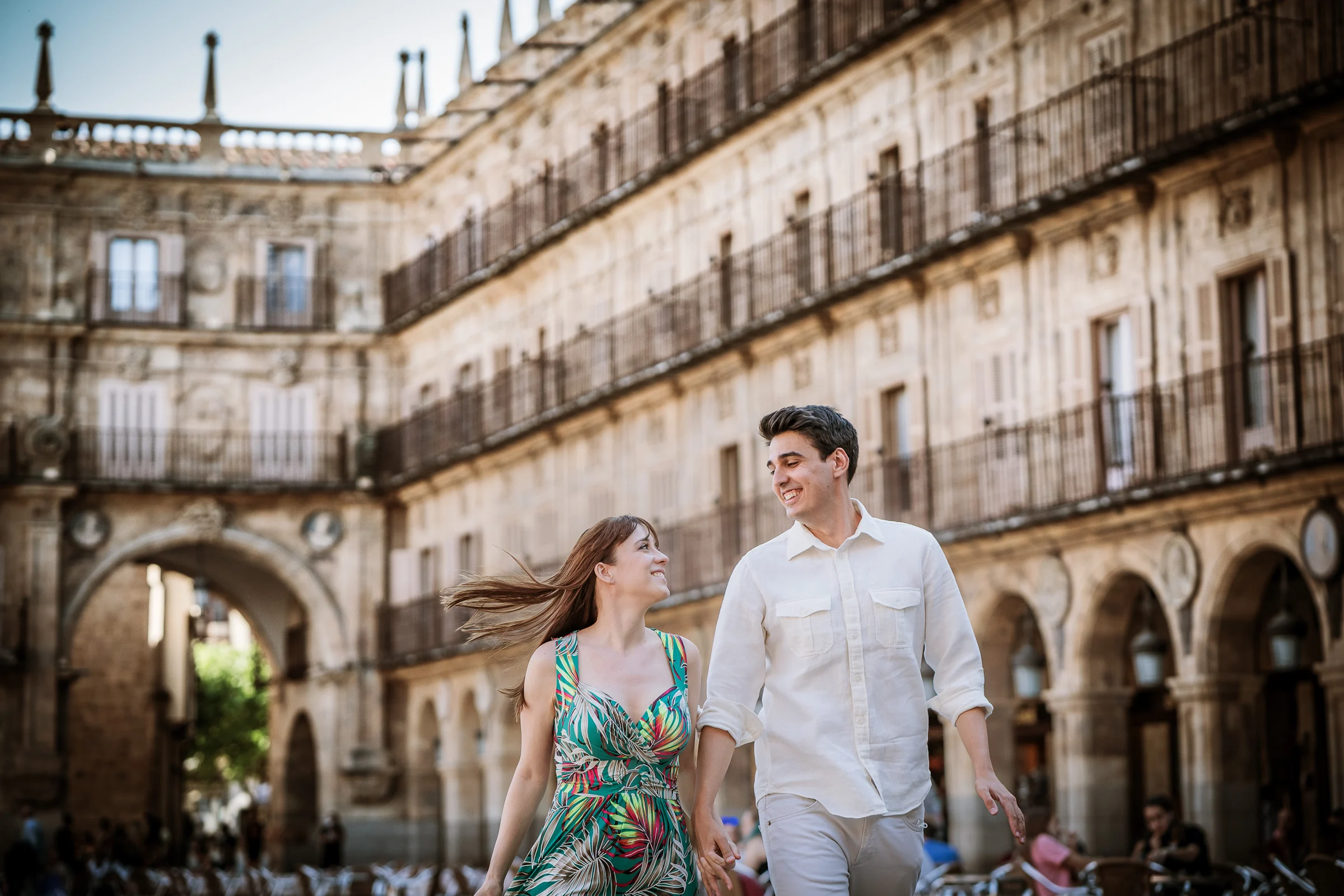 David y Noelia caminan por la Plaza Mayor de Salamanca rodeados por su arquitectura de piedra.