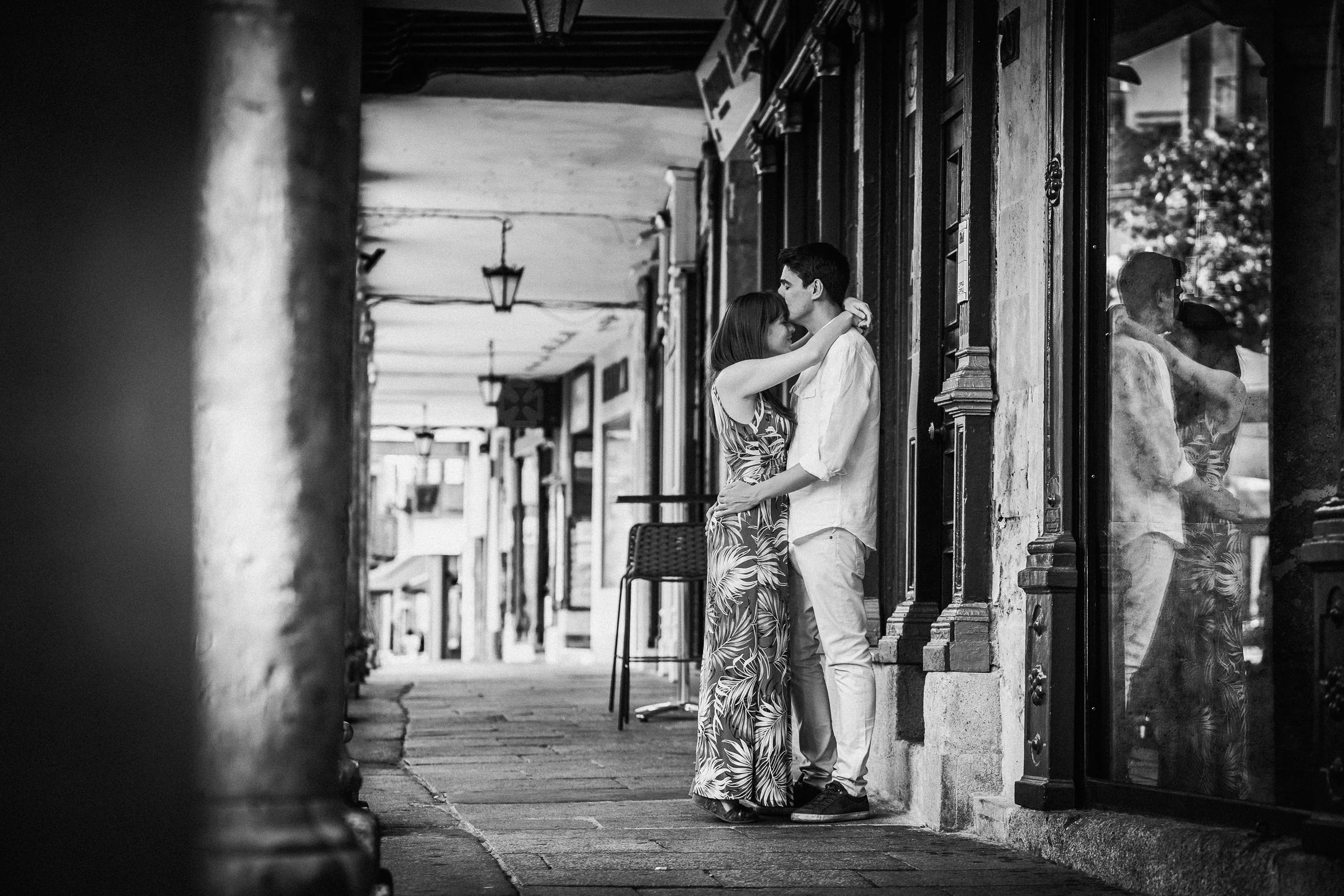 David y Noelia se abrazan en blanco y negro en una calle porticada del centro histórico de Salamanca.