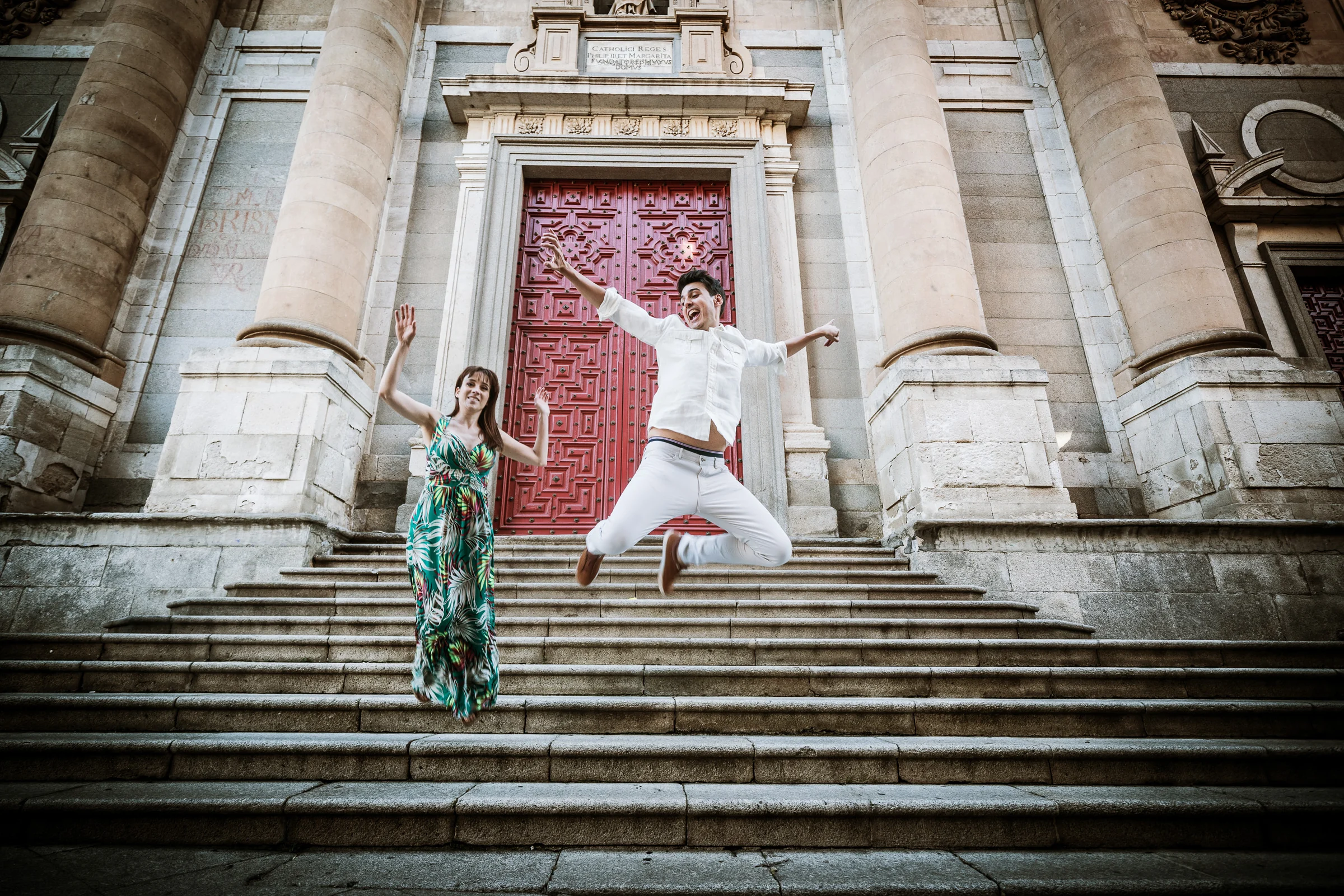 David y Noelia juegan en la escalinata de un edificio histórico durante su preboda en Salamanca.