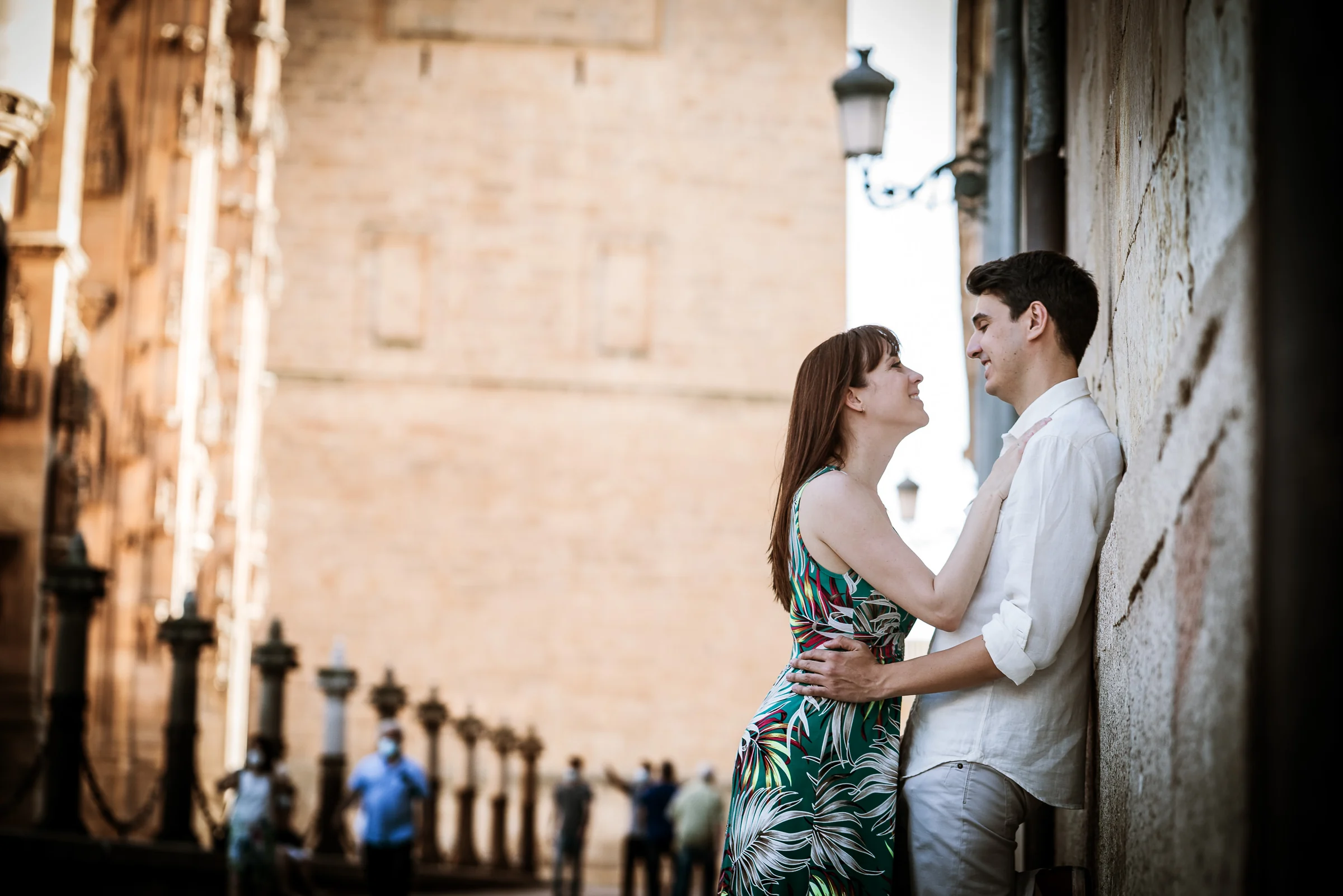 David y Noelia se miran junto a una fachada de piedra durante su paseo de preboda por Salamanca.
