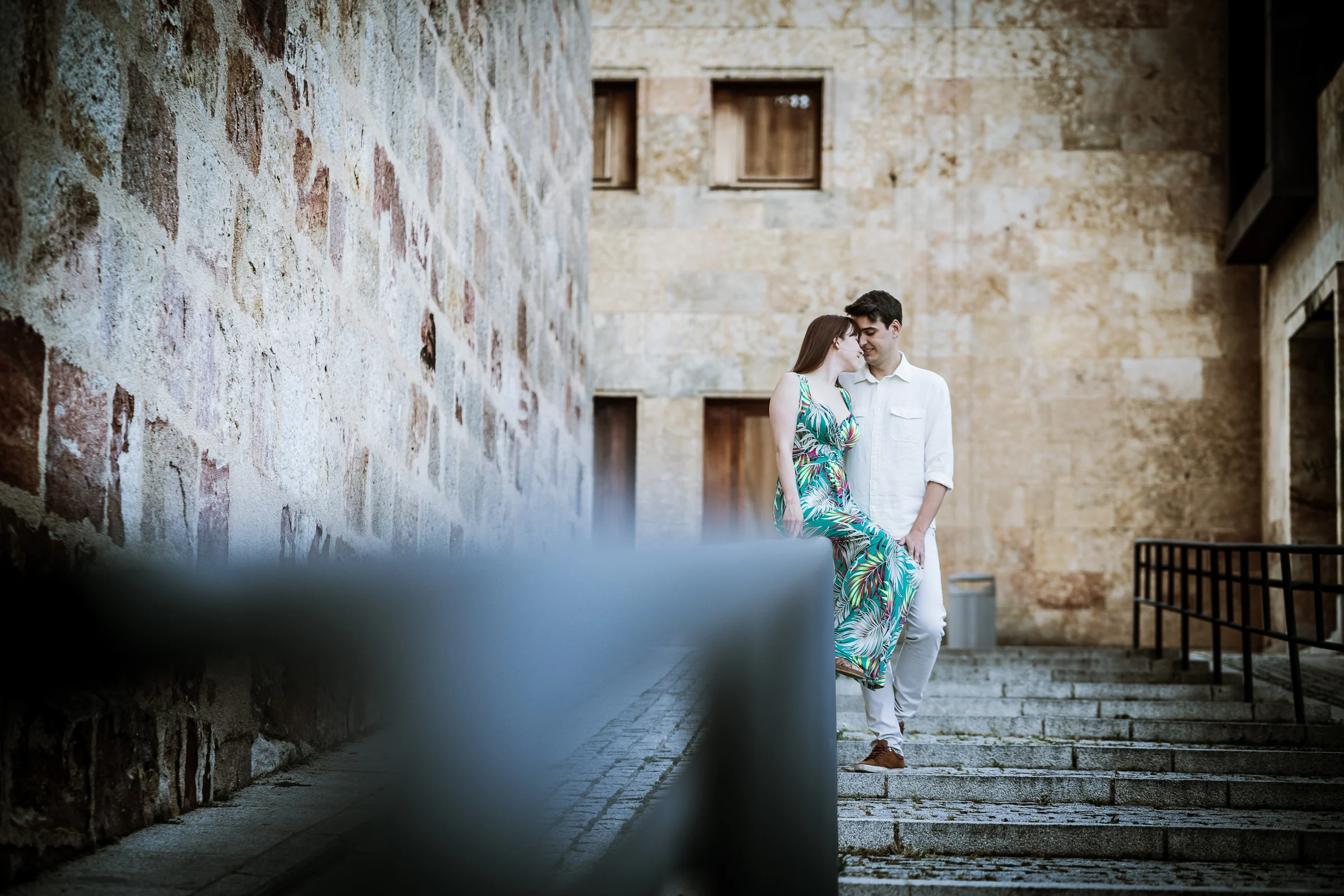David y Noelia recorren unos escalones junto a un muro de piedra en el casco histórico de Salamanca.