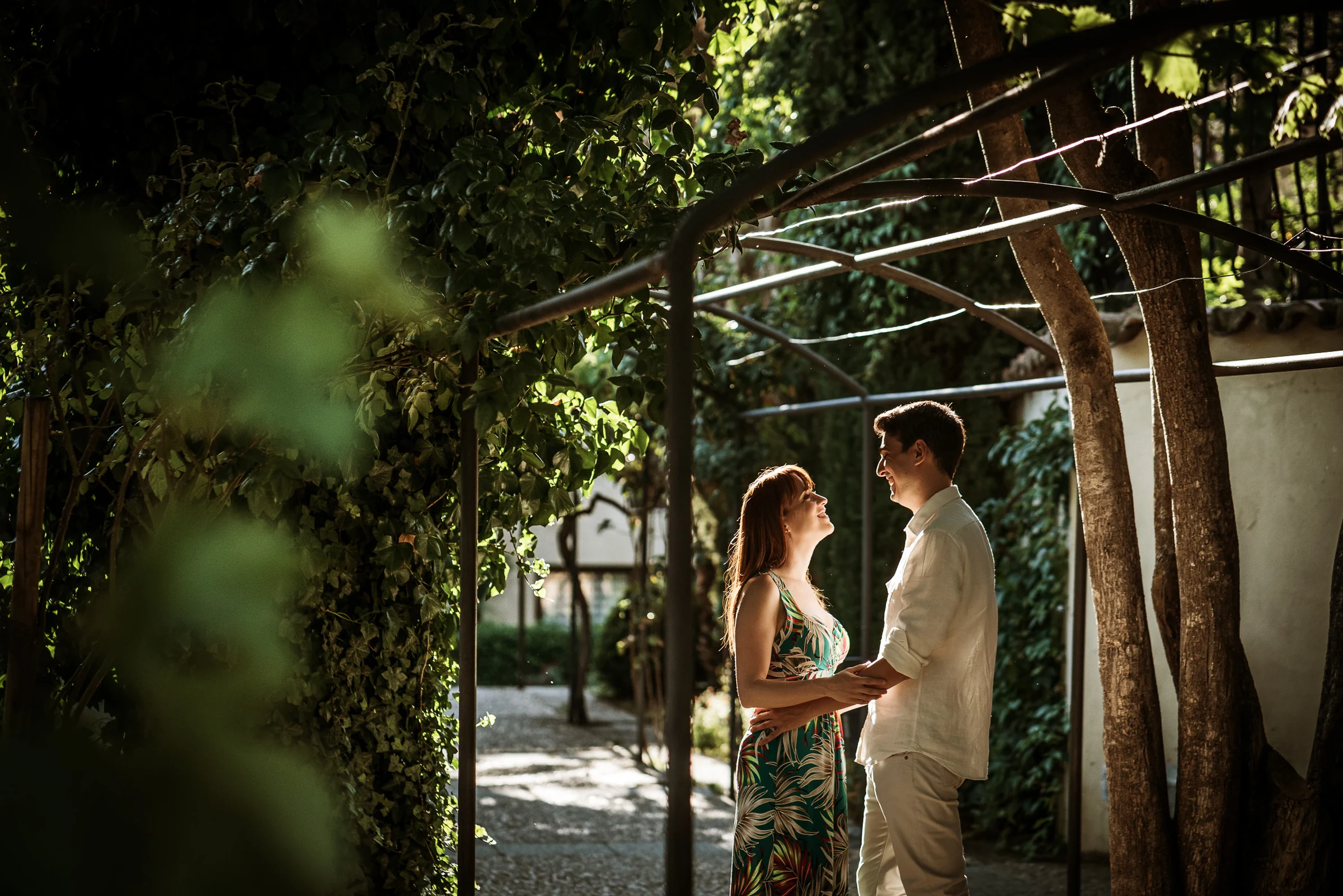 David y Noelia se miran bajo una pérgola rodeada de vegetación durante su preboda en Salamanca.