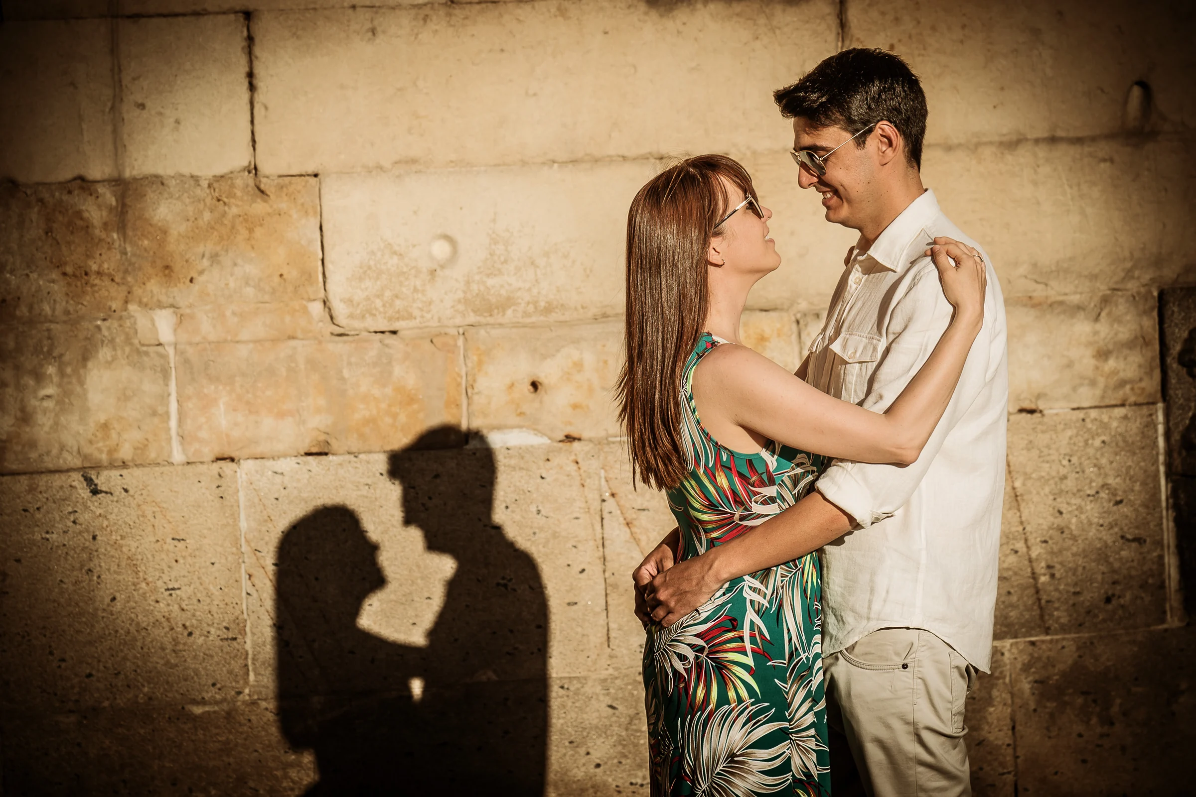 David y Noelia posan junto a un muro de piedra mientras sus sombras se proyectan durante la preboda en Salamanca.