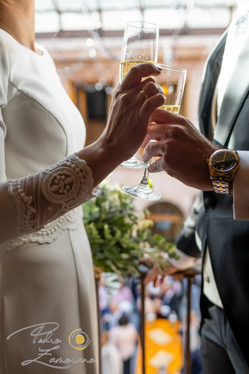 Detalle de las manos de los novios brindando con copas de espumoso.