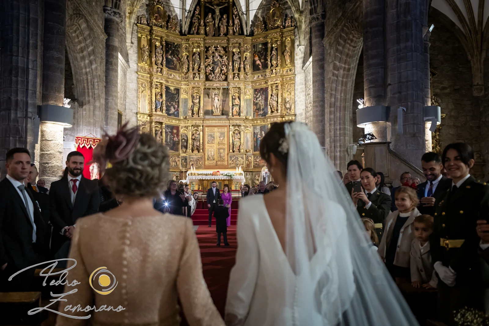 Novia entrando en una iglesia acompañada mientras los invitados la esperan.