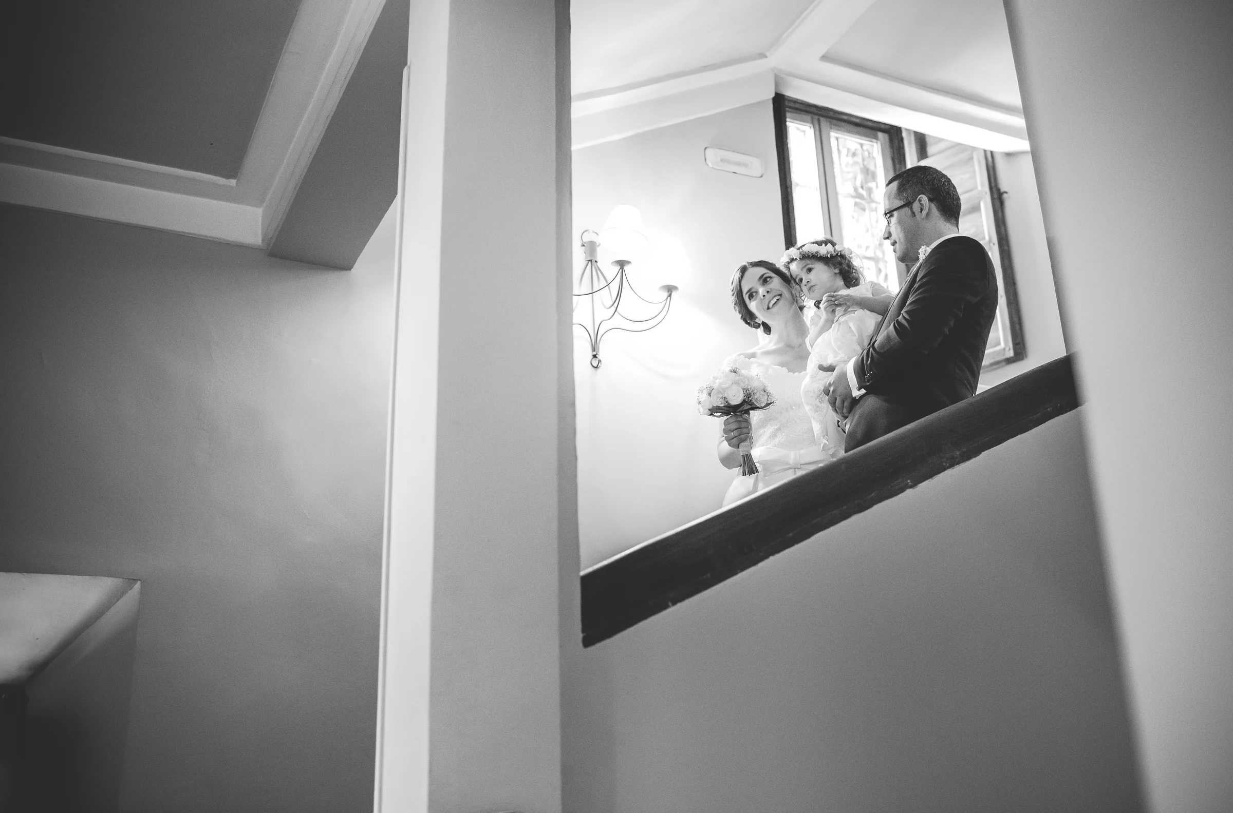 Pareja con una niña en una escalera interior en una fotografía en blanco y negro.