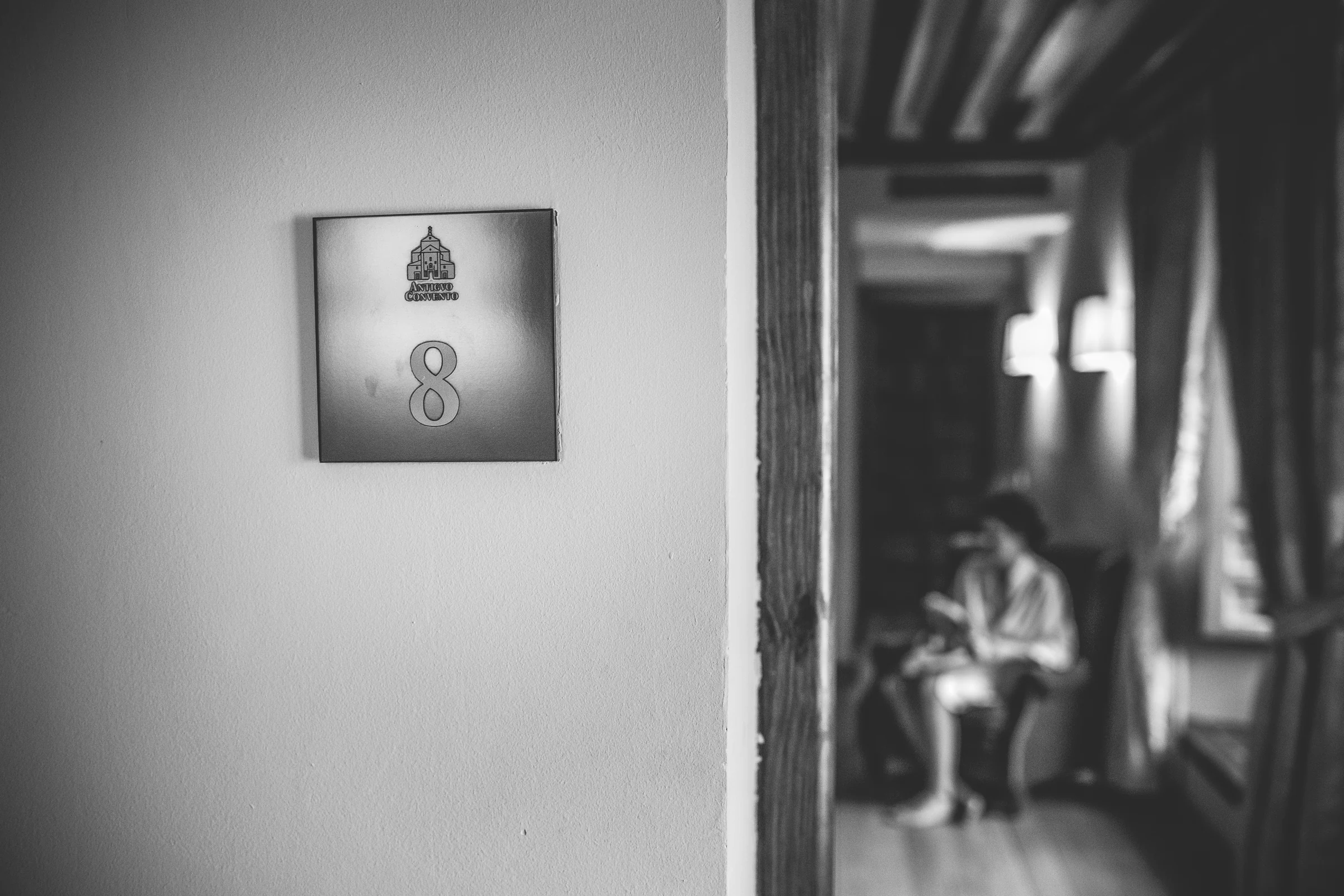 Placa de la habitación ocho con la novia desenfocada al fondo del pasillo.