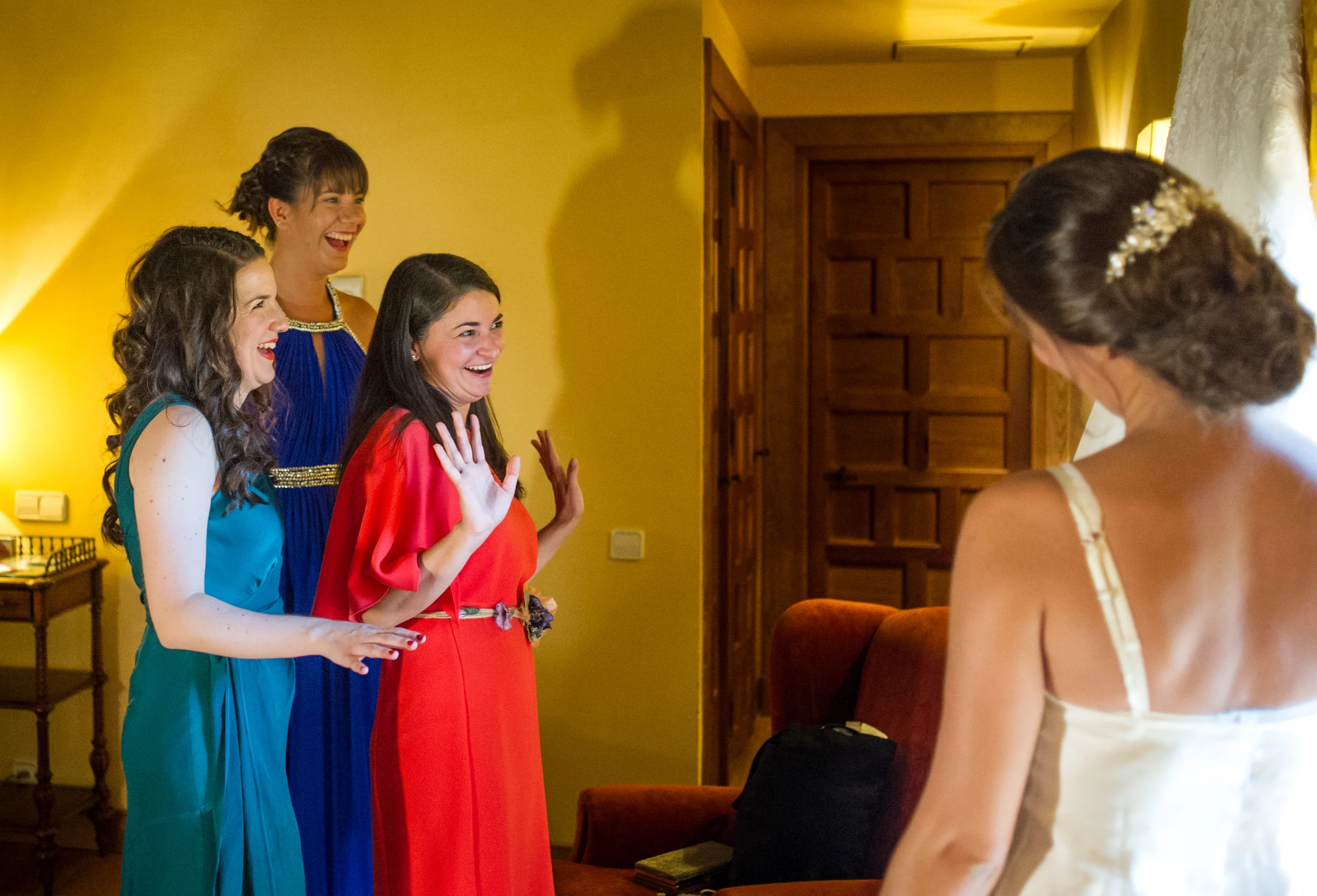 Amigas reaccionando con alegría al ver a la novia ya preparada.