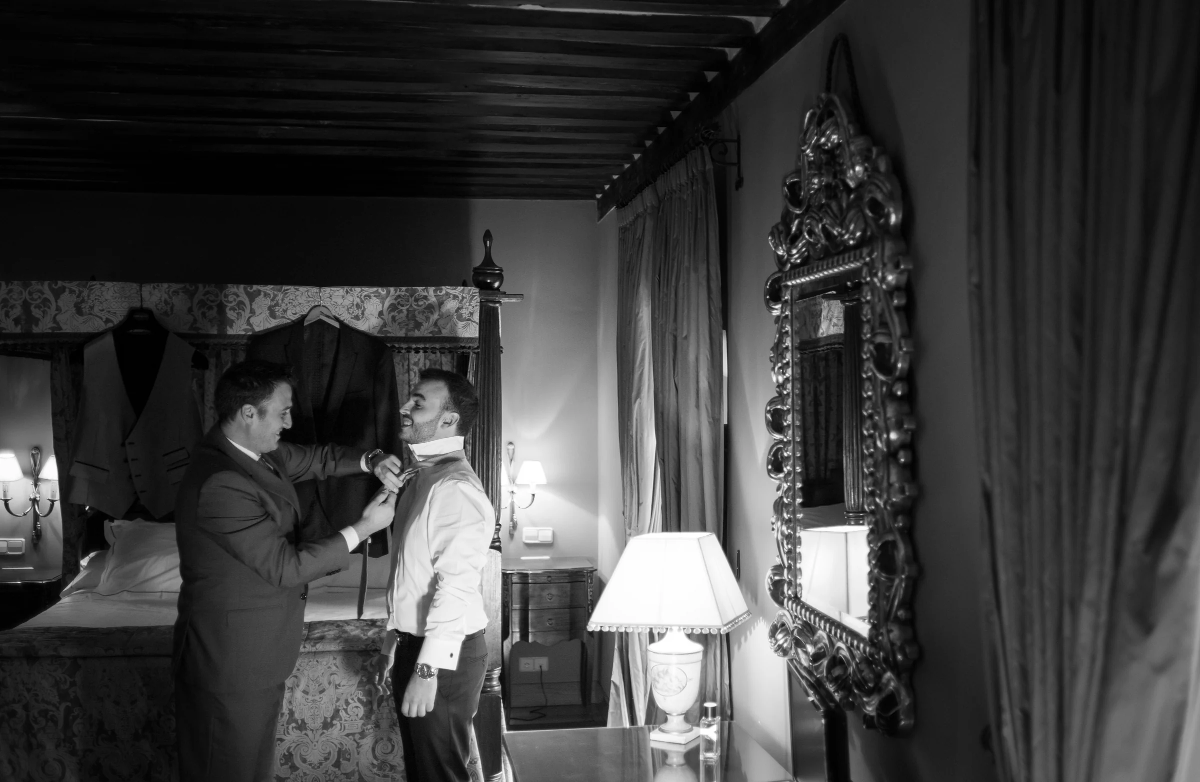 Hombre ayudando al novio a colocar la corbata antes de la ceremonia.