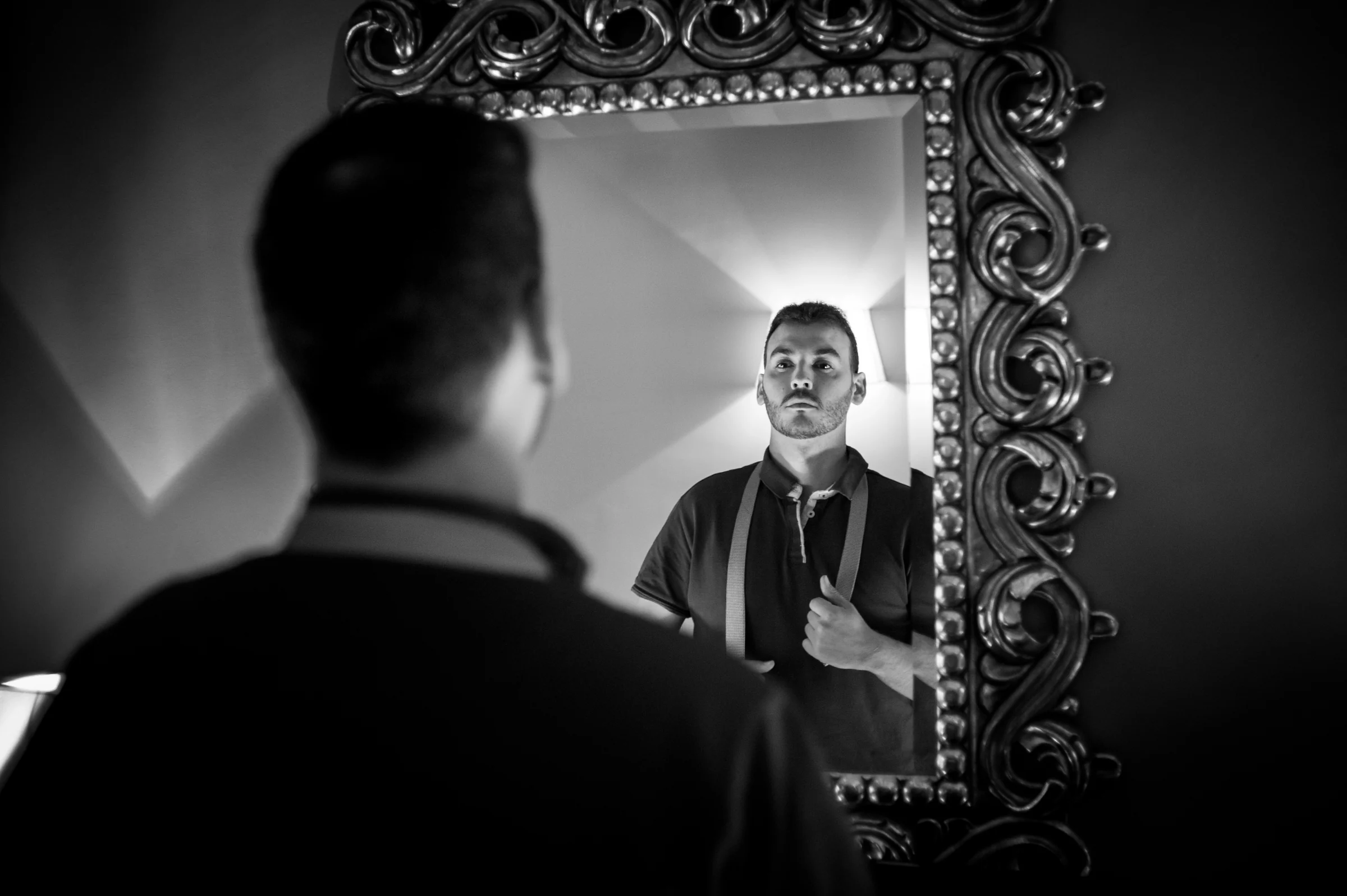 Novio mirándose en un espejo en blanco y negro durante los preparativos.