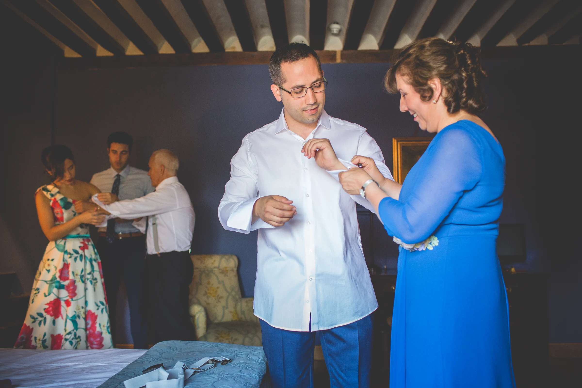 Mujer ayudando al novio con el puño de la camisa durante los preparativos.