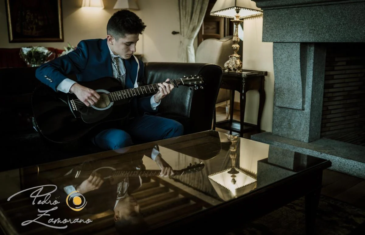 Novio tocando la guitarra durante los preparativos de boda en una habitación.