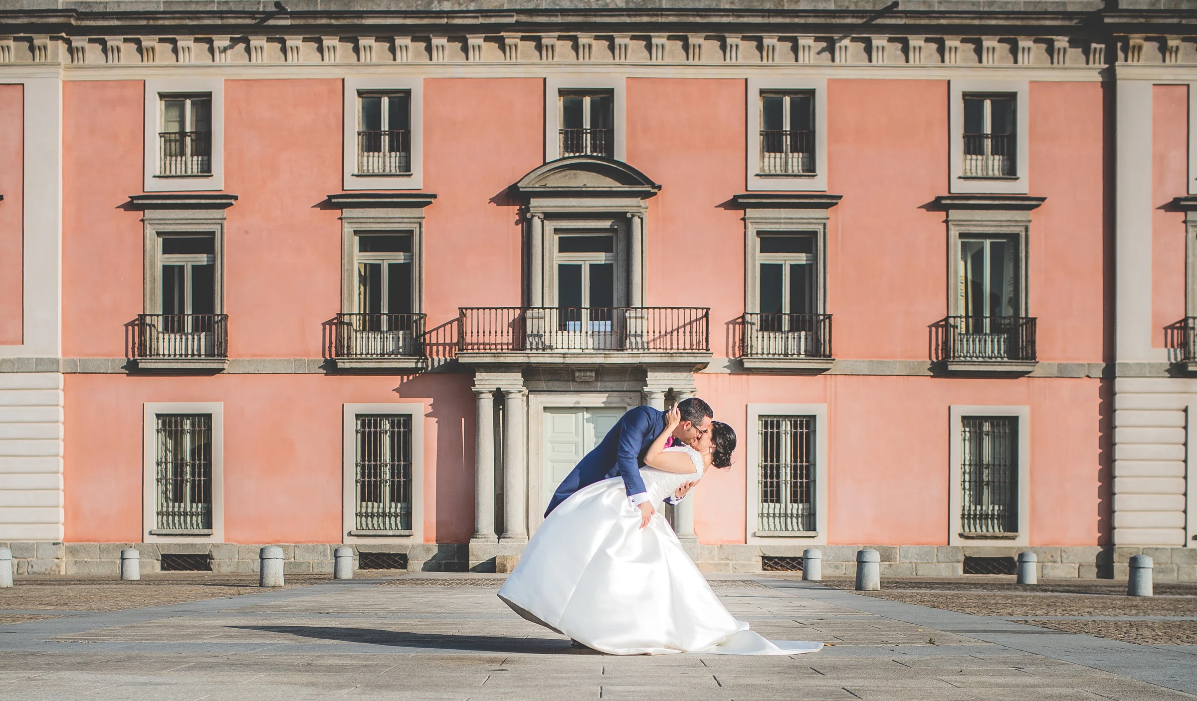 Novio inclinando a la novia para besarla frente al palacio de Boadilla del Monte.