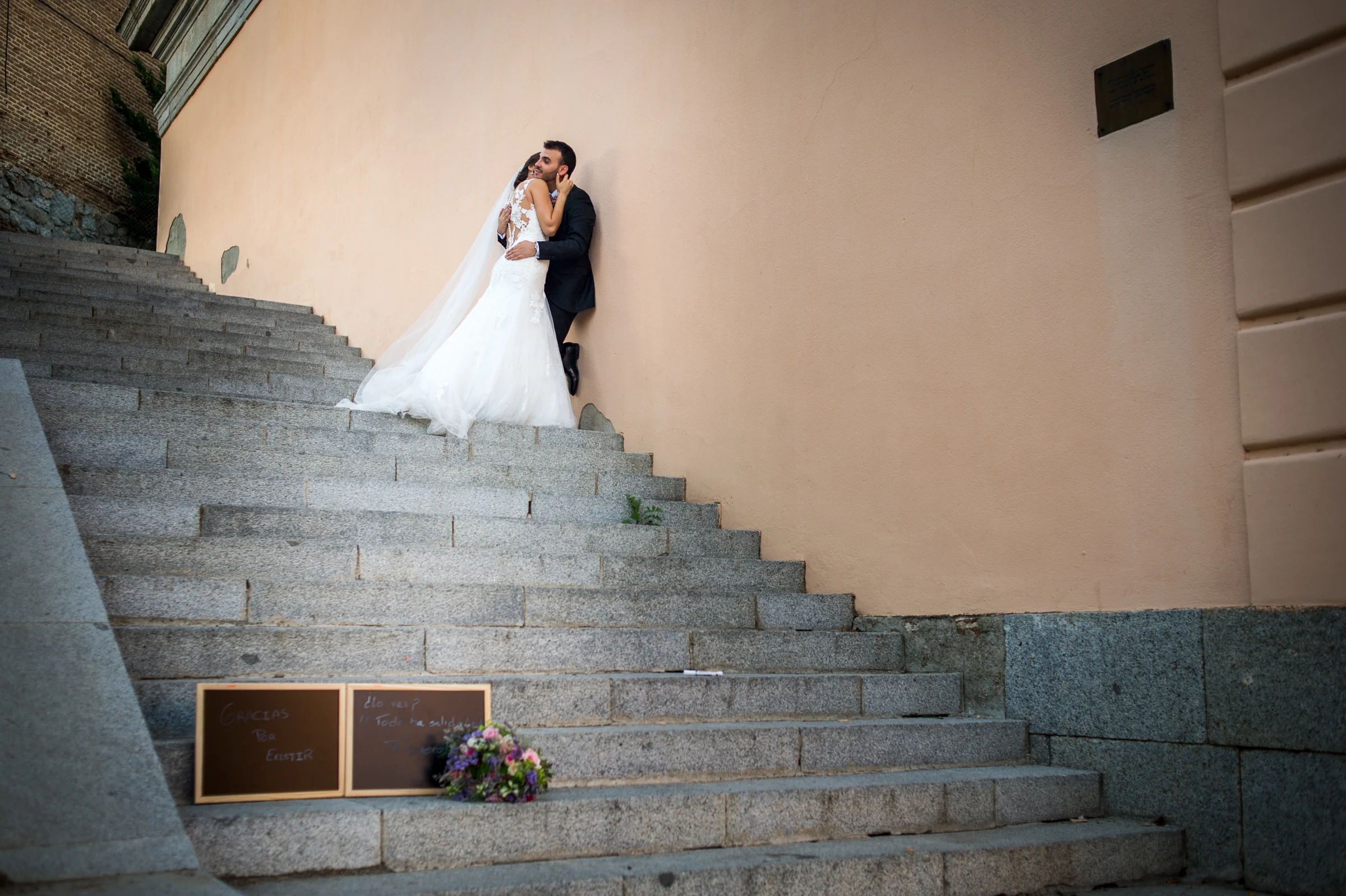 Pareja abrazada en la parte alta de una gran escalera exterior.