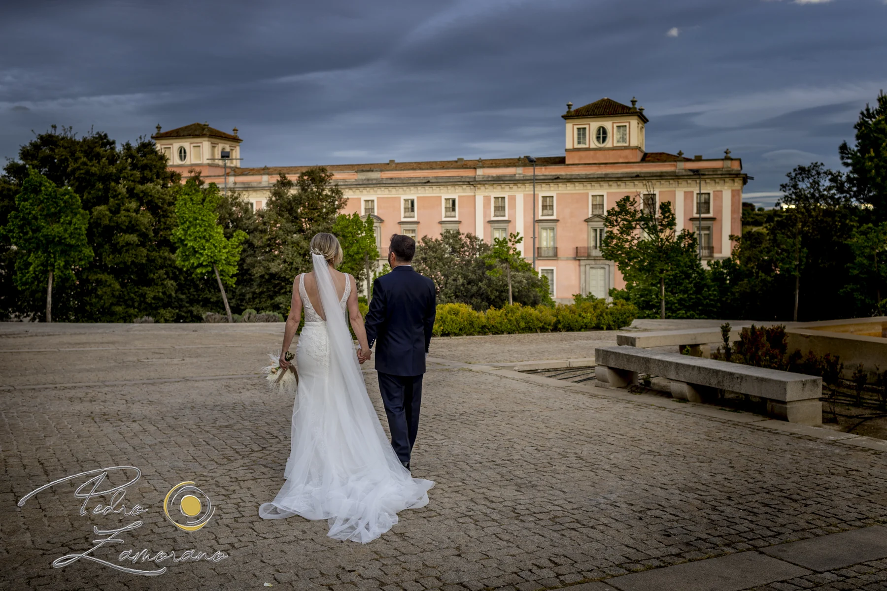 Pareja de recién casados caminando frente al palacio en Boadilla del Monte.