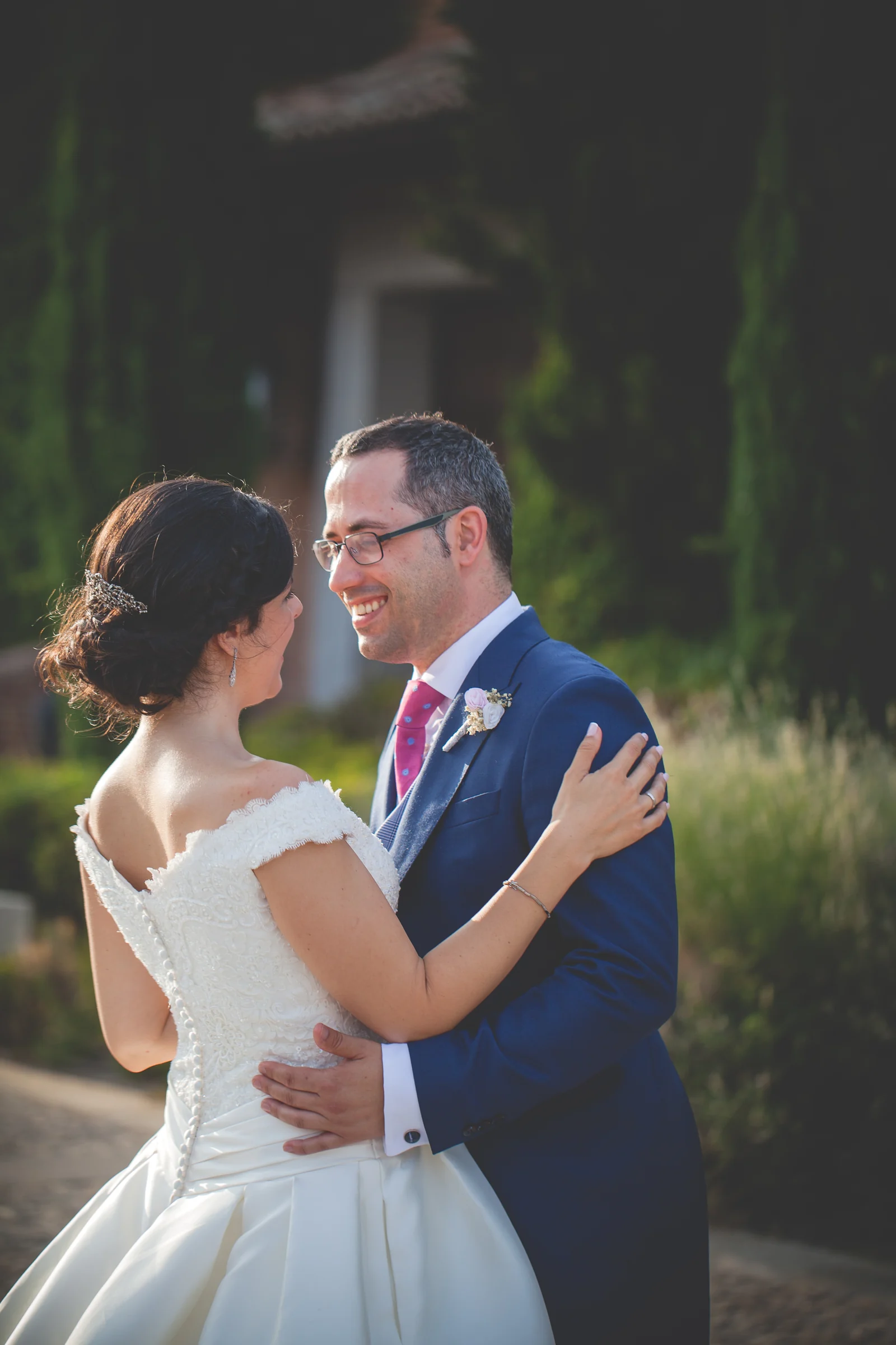 Pareja de novios sonriendo y abrazándose durante la sesión exterior.