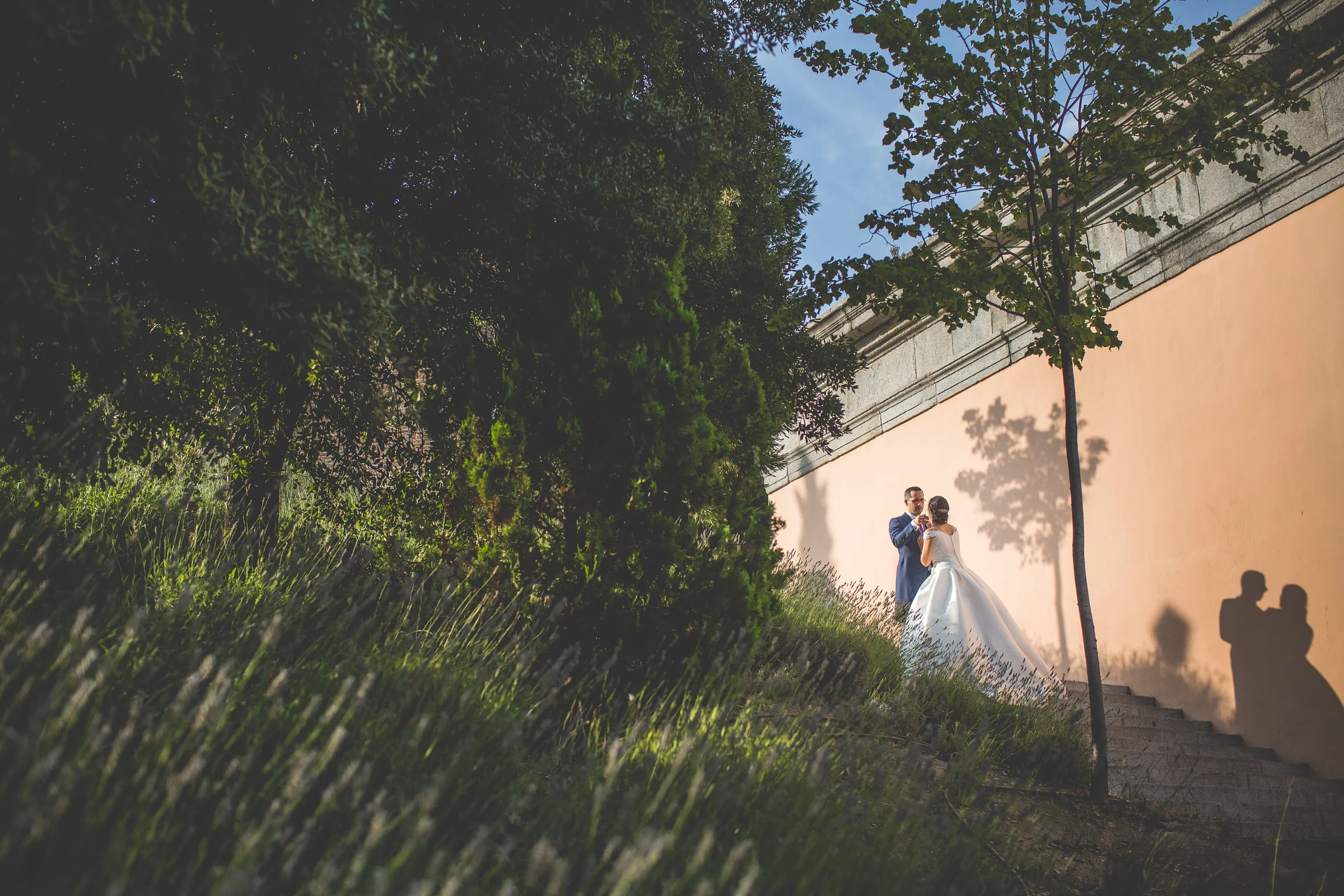 Pareja de novios junto a un muro con sus sombras proyectadas por el sol.