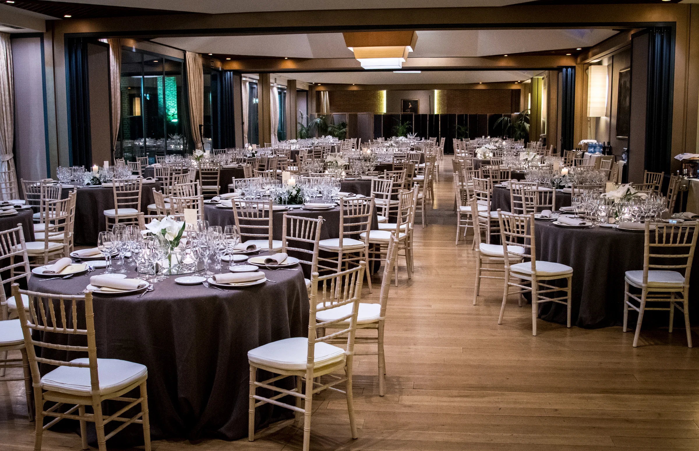 Salón de banquete preparado con mesas redondas y sillas para una boda.