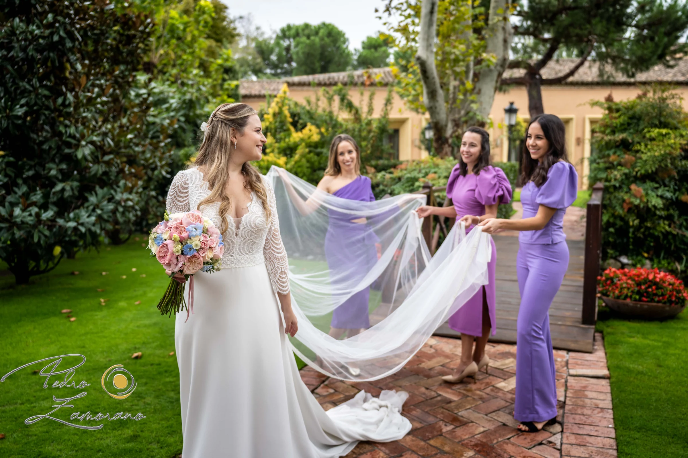 Novia con sus acompañantes y el velo en los jardines de Finca La Alquería