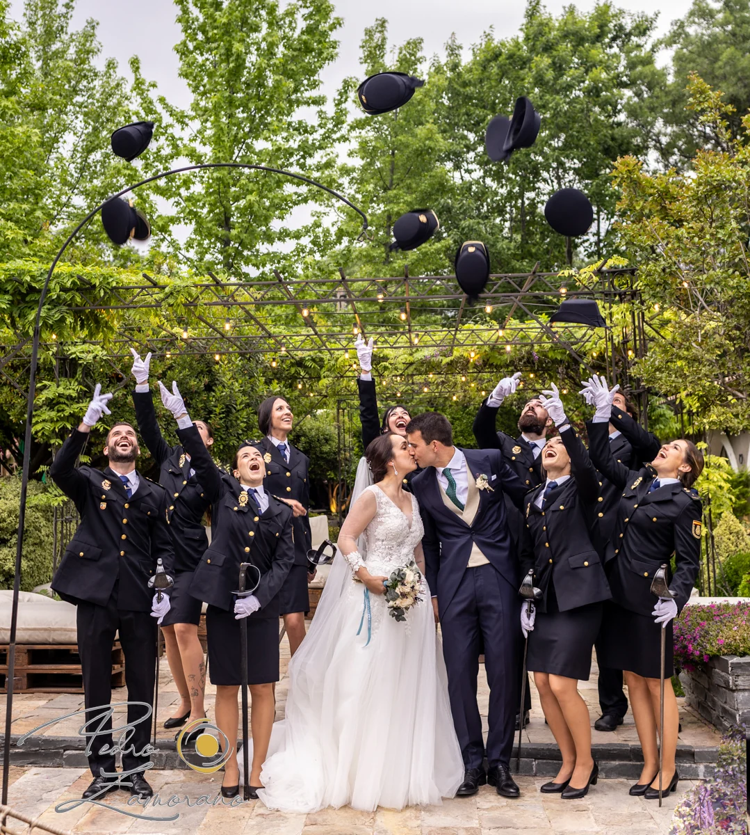 Novios besándose rodeados por compañeros uniformados durante la celebración en Hacienda Jacaranda.