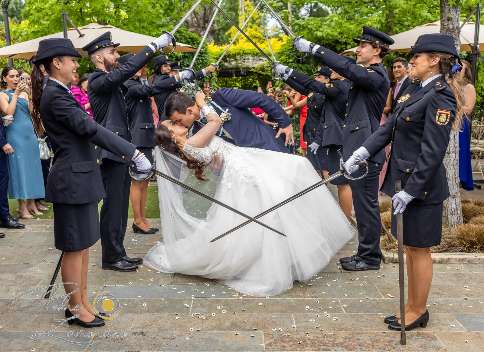 Novios besándose bajo un arco de sables durante la salida de la ceremonia en Hacienda Jacaranda.