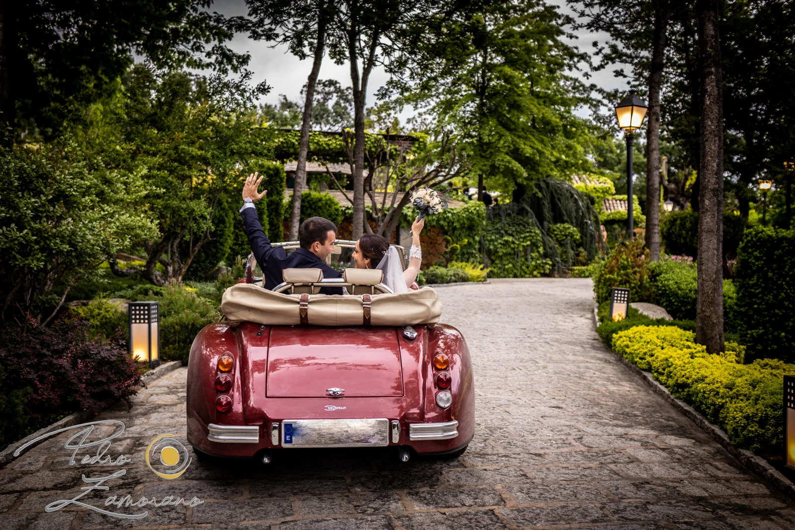 Novios en un coche clásico descapotable recorriendo los jardines de Hacienda Jacaranda.