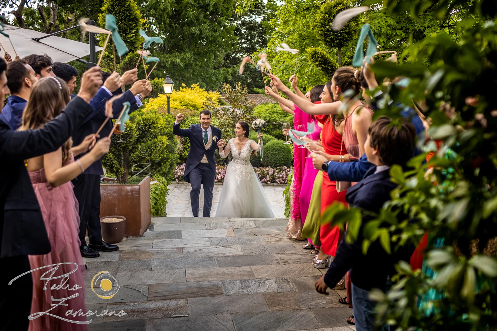 Entrada de los novios entre invitados en uno de los caminos ajardinados de Hacienda Jacaranda.