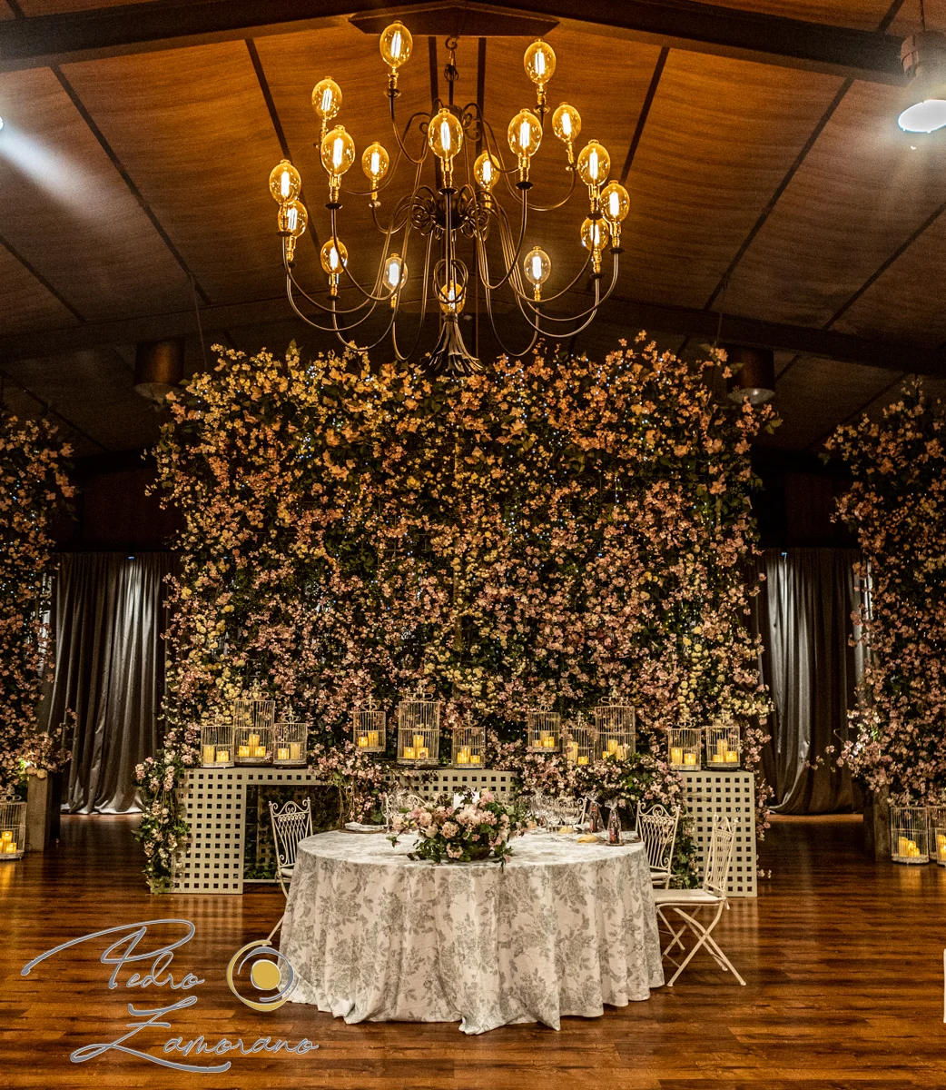 Mesa presidencial decorada con flores y velas en el salón de Hacienda Jacaranda.