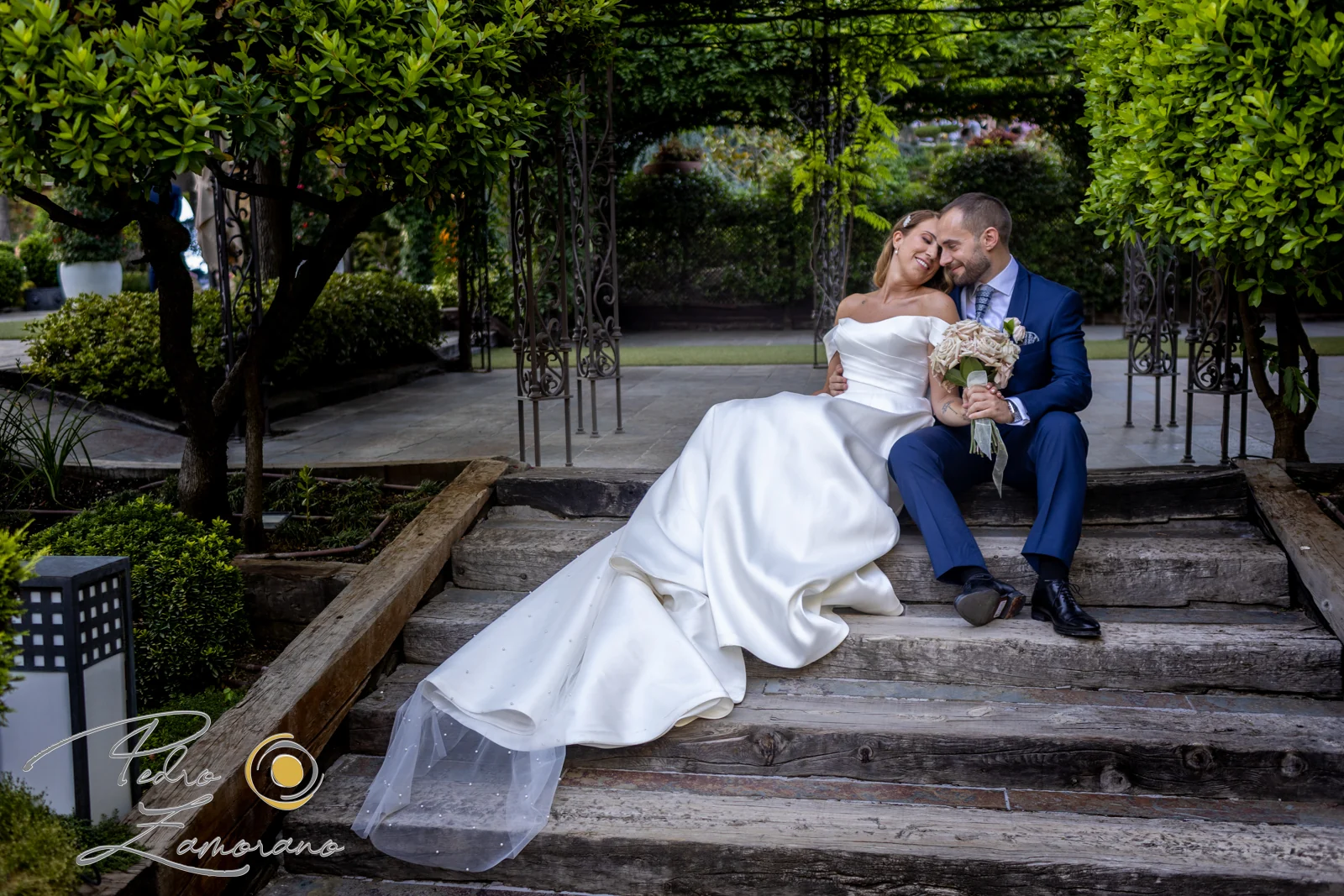 Novios sentados juntos en los escalones del jardín de Hacienda Jacaranda.