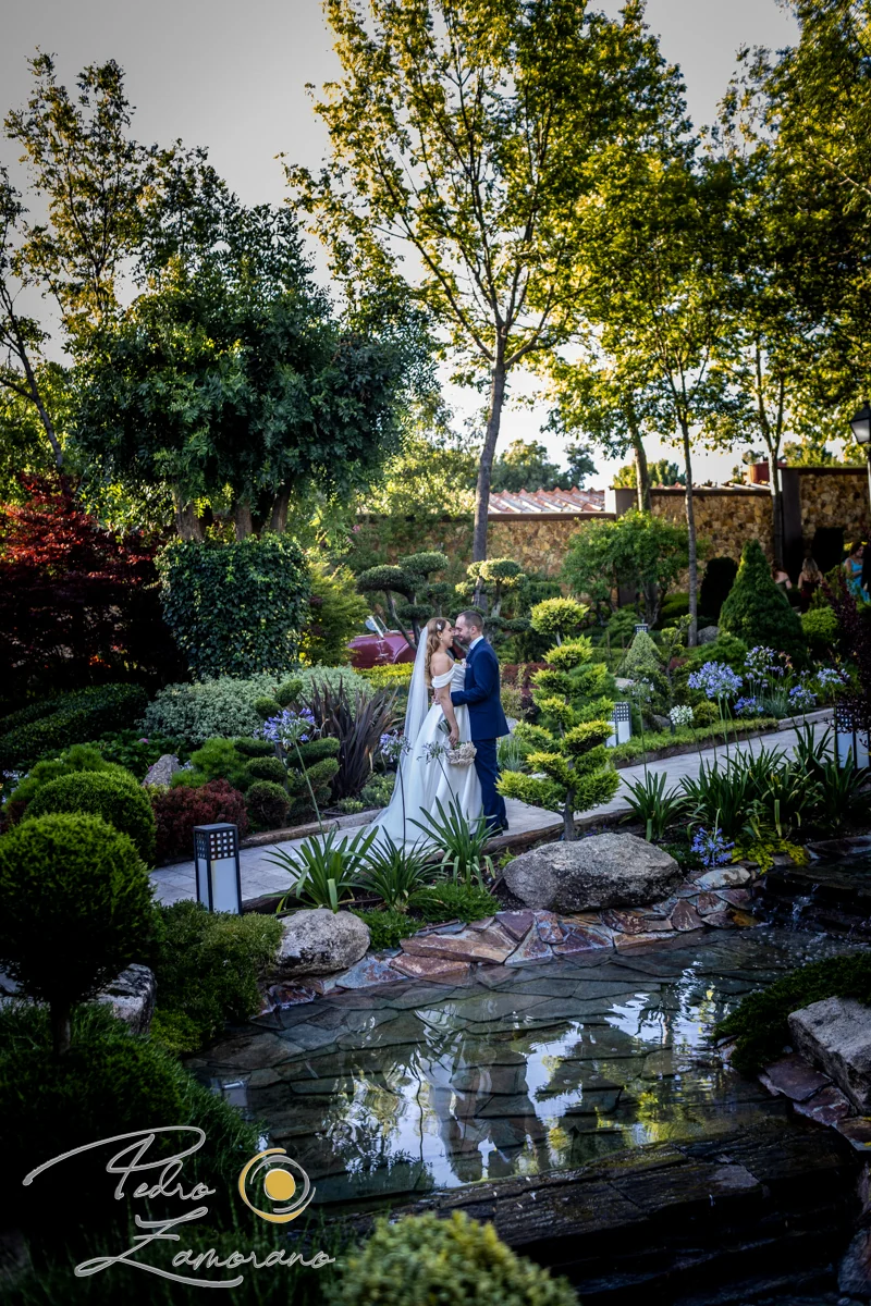 Pareja fotografiada junto al estanque y la vegetación de los jardines de Hacienda Jacaranda.