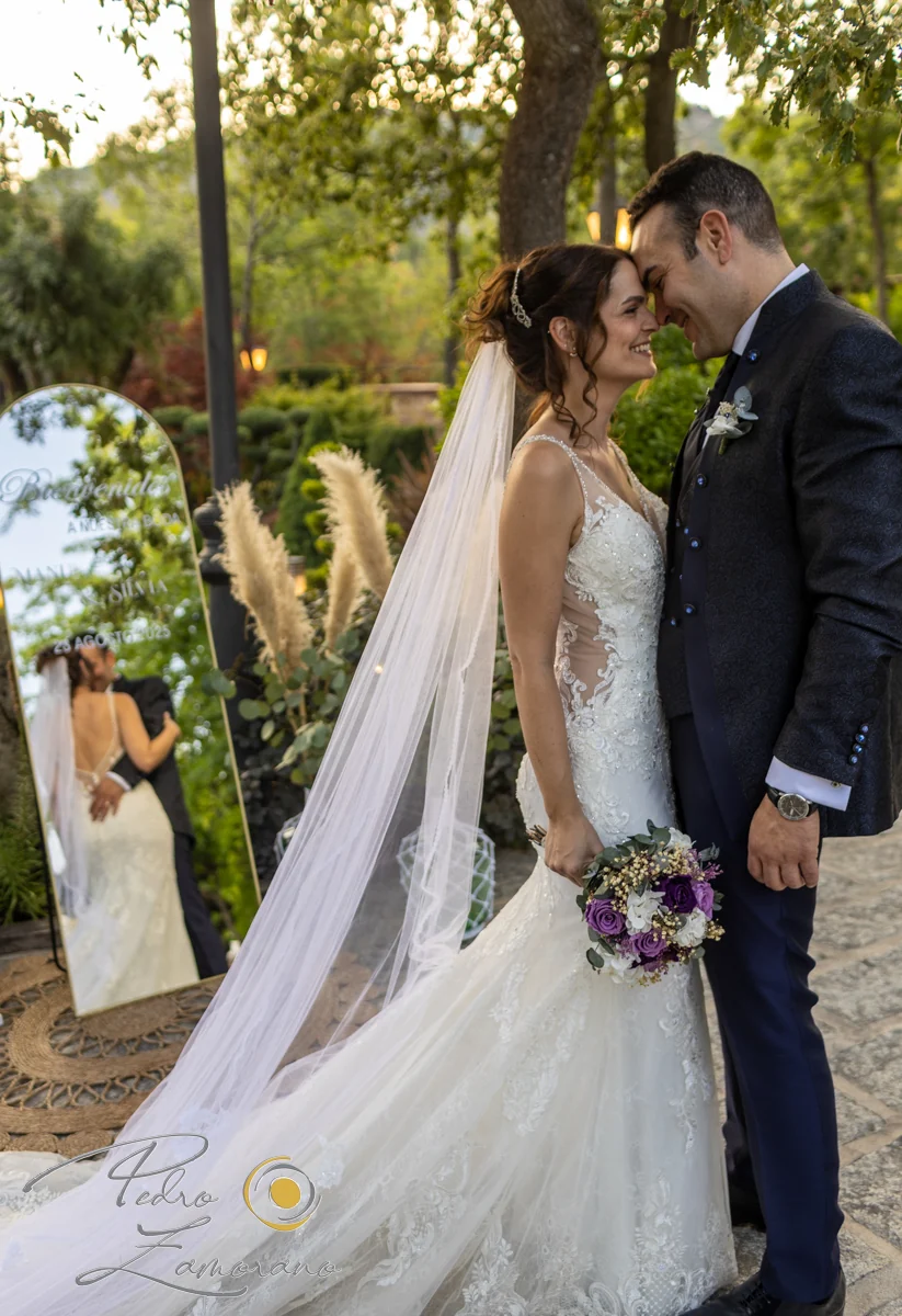 Pareja de novios junto a un espejo decorativo entre los jardines de Hacienda Jacaranda.